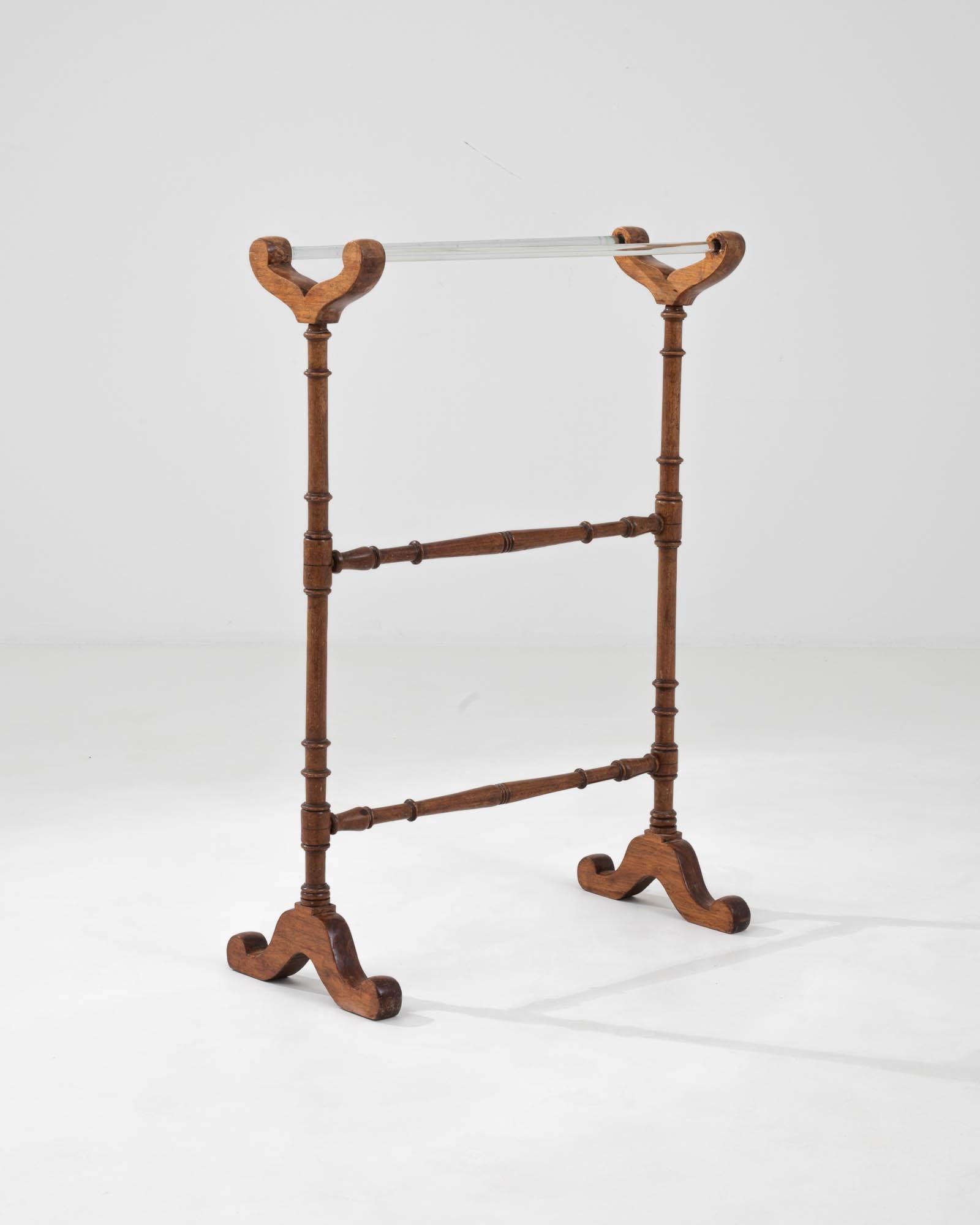 Eleganza e raffinatezza nel tuo spazio abitativo con questo elegante appendiabiti francese del XX secolo in legno e vetro. Realizzato con una meticolosa attenzione ai dettagli, questo pezzo presenta una calda struttura in legno con delicati fusi