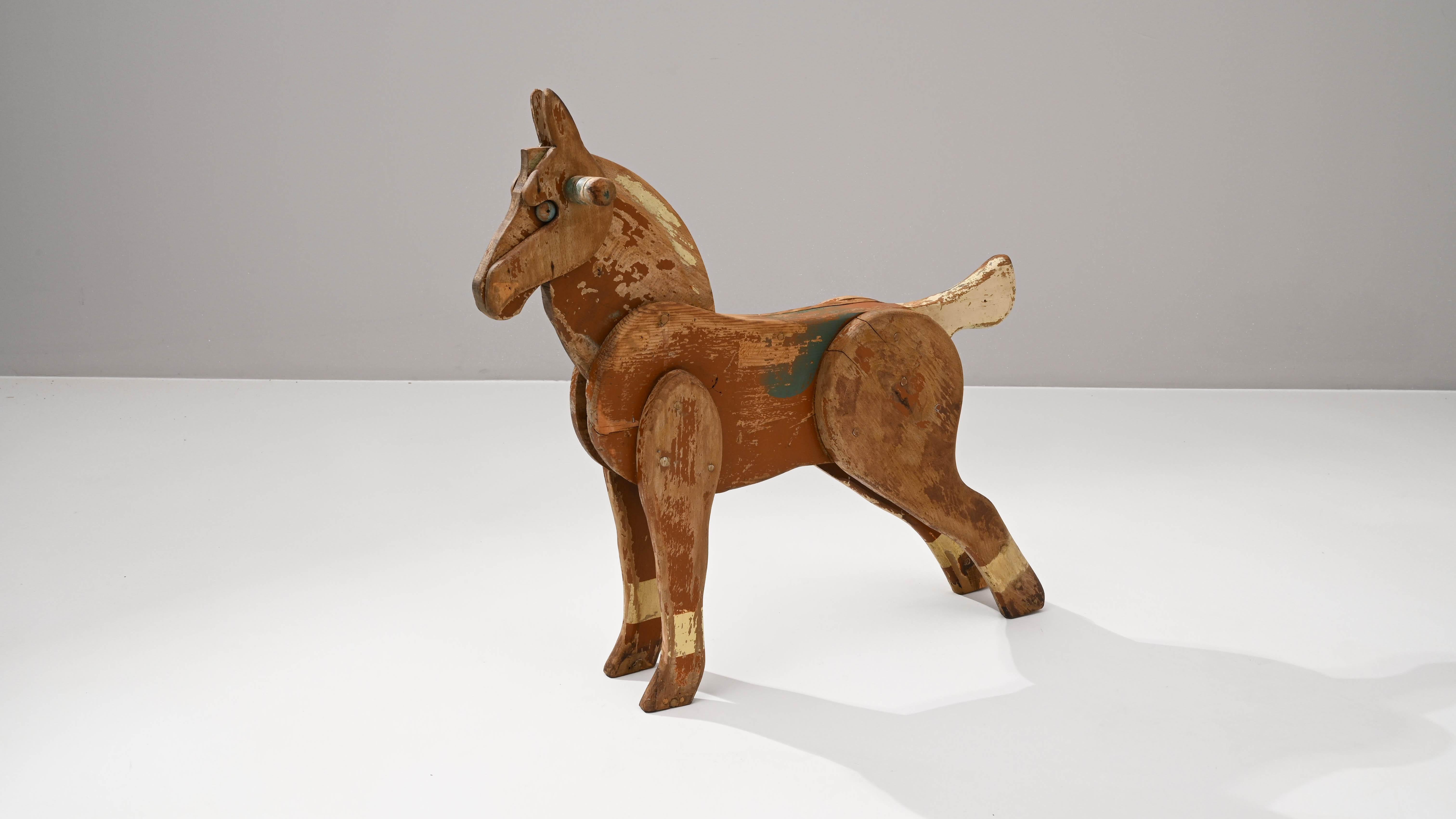 Entdecken Sie ein Stück Geschichte mit diesem französischen Holzpferd aus dem 20. Jahrhundert, ein handgefertigtes Stück, das zeitlosen Charme und Charakter ausstrahlt. Dieser Schatz der Volkskunst erzählt mit seiner verwitterten Patina und seiner