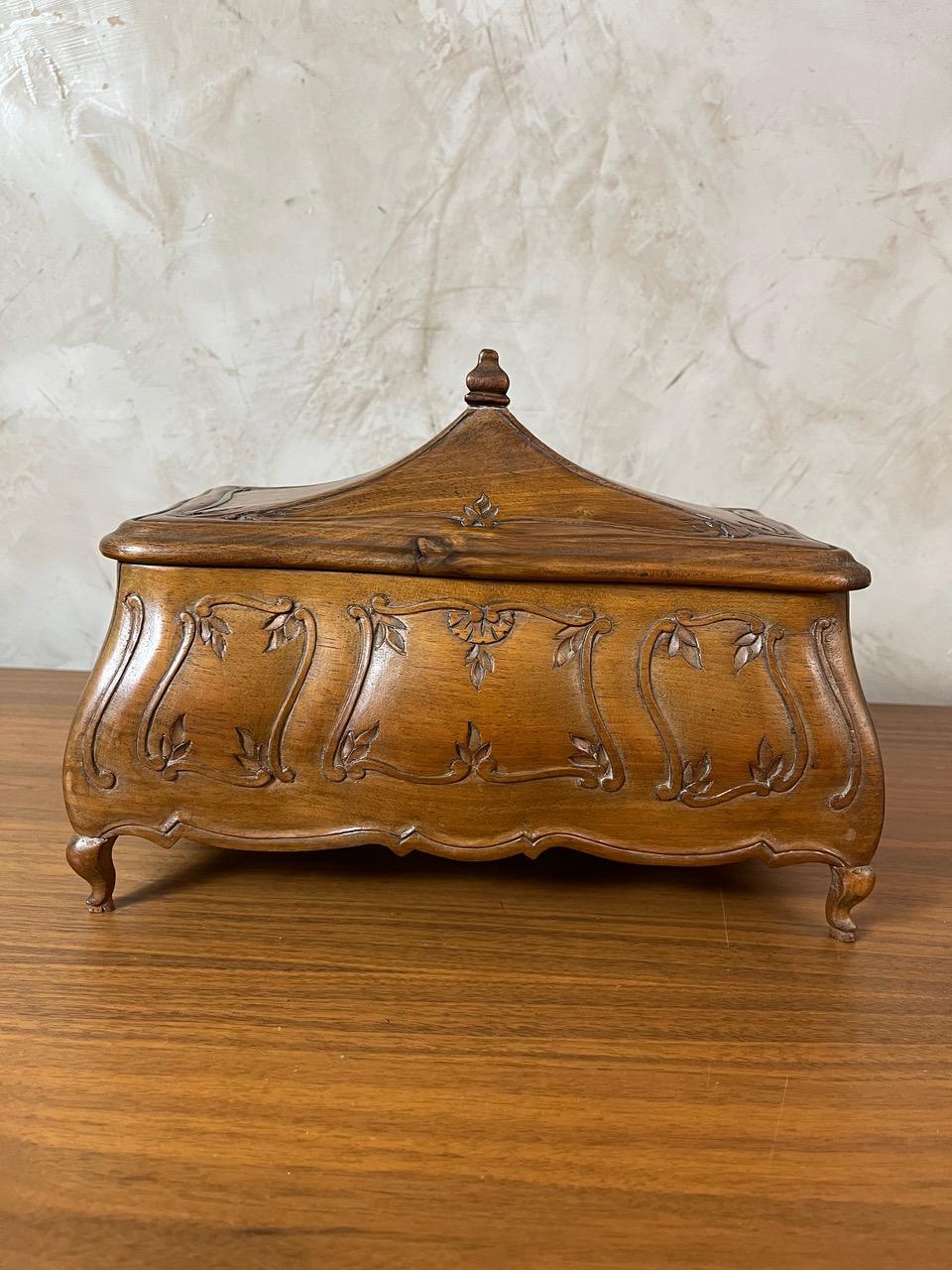 Schmuckkästchen aus Holz im Stil Louis XV mit einer raffinierten Silhouette mit eleganten Kurven und fein geschnitzten Blumenmotiven. Der Innenraum ist mit rosa Stoff ausgekleidet. Sein gewölbter Deckel ist mit einem kleinen Zierknopf versehen, der
