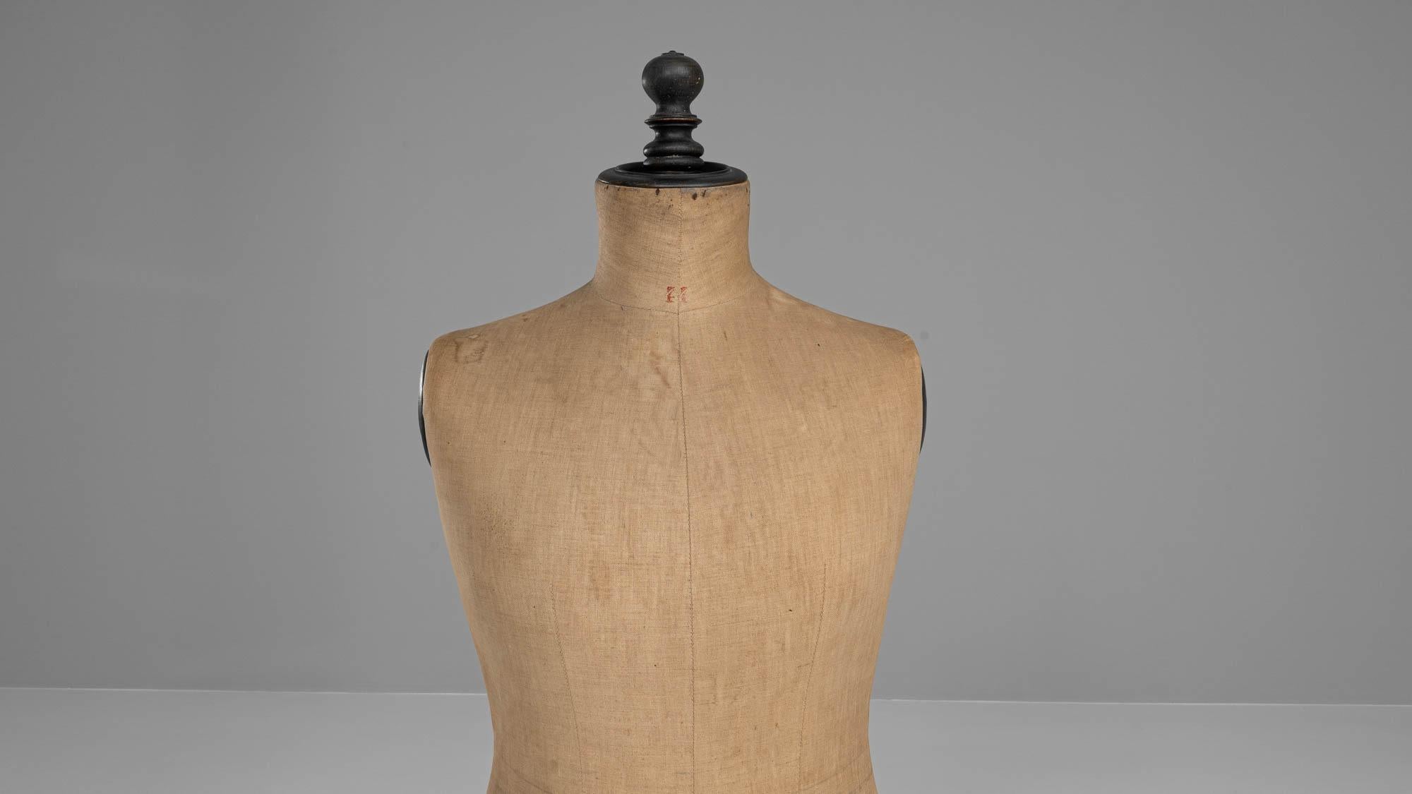 Capture the essence of early 20th-century French craftsmanship with this Antique French Wooden Mannequin. Crafted with precision, this unique piece showcases the silhouette of a woman and stands on a turned stand with a weathered tripod base. The