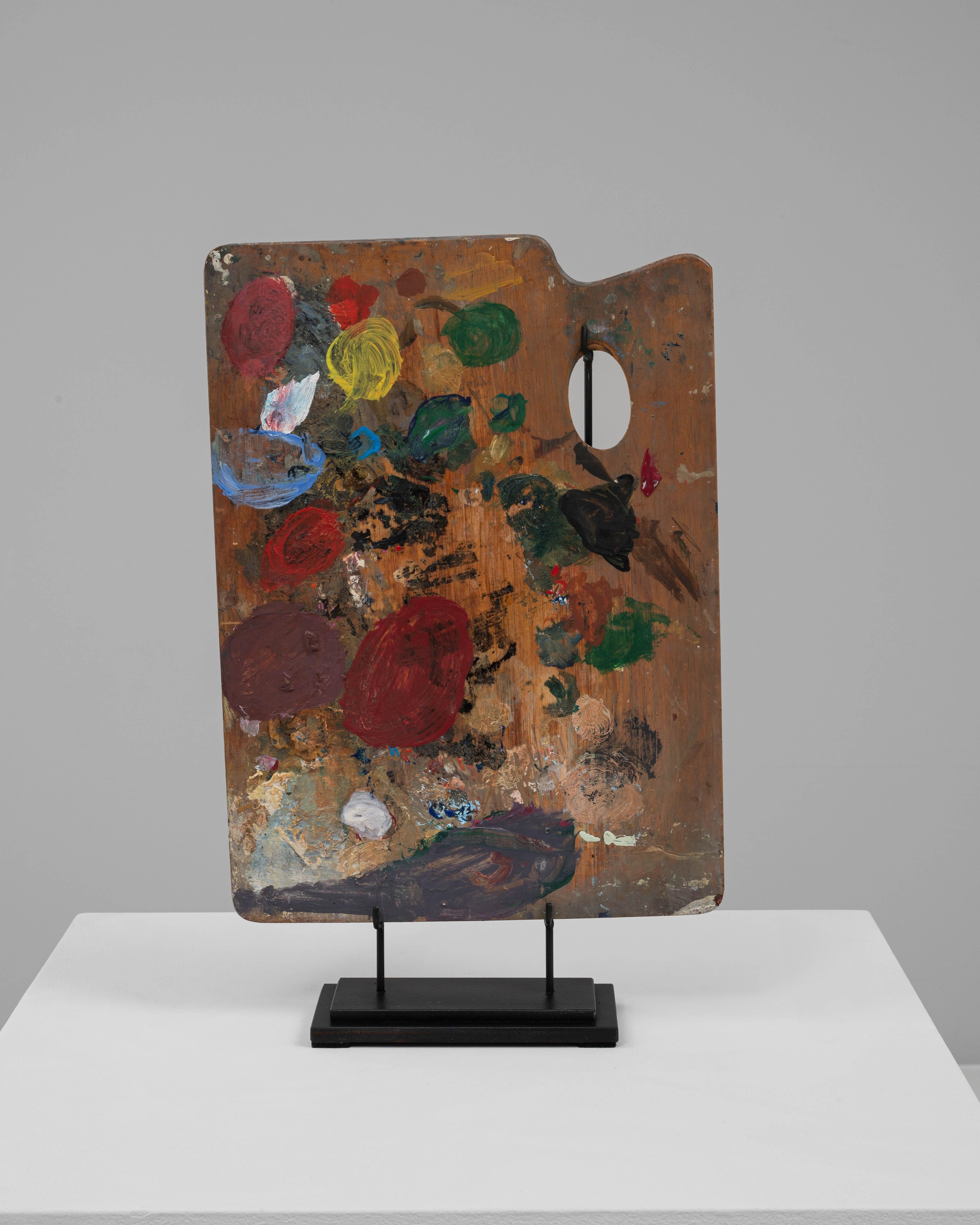 Cette palette de peintre française en bois du XXe siècle est un artefact magnifiquement préservé du processus artistique, élevé sur un support métallique personnalisé pour l'exposition. La surface conserve ses couches de peinture expressives et