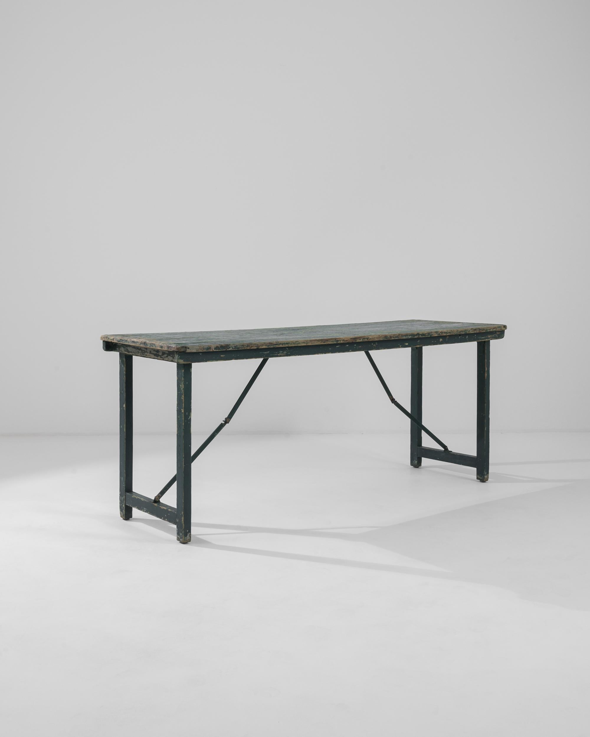 Table de salle à manger en bois du XXe siècle produite en France, cette belle table pliante patinée est un bijou de simplicité et de fonctionnalité. Présentant une riche palette de vert forêt avec des nuances de jade et de sarcelle, la patine