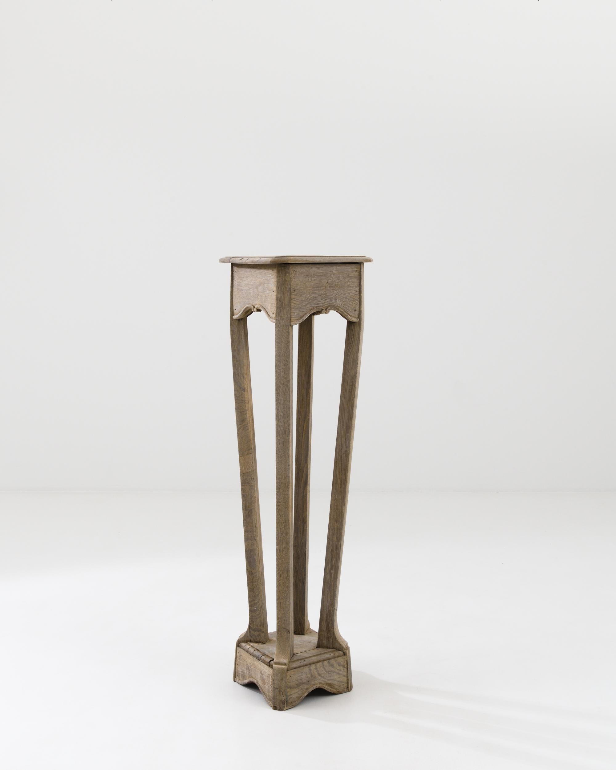 A wooden pedestal created in 20th century France. Slender, swooping legs gracefully descend downwards from this pedestal’s top, reminiscent of the shape of a squid propelling itself forward underwater. A delicate bleaching process has been applied