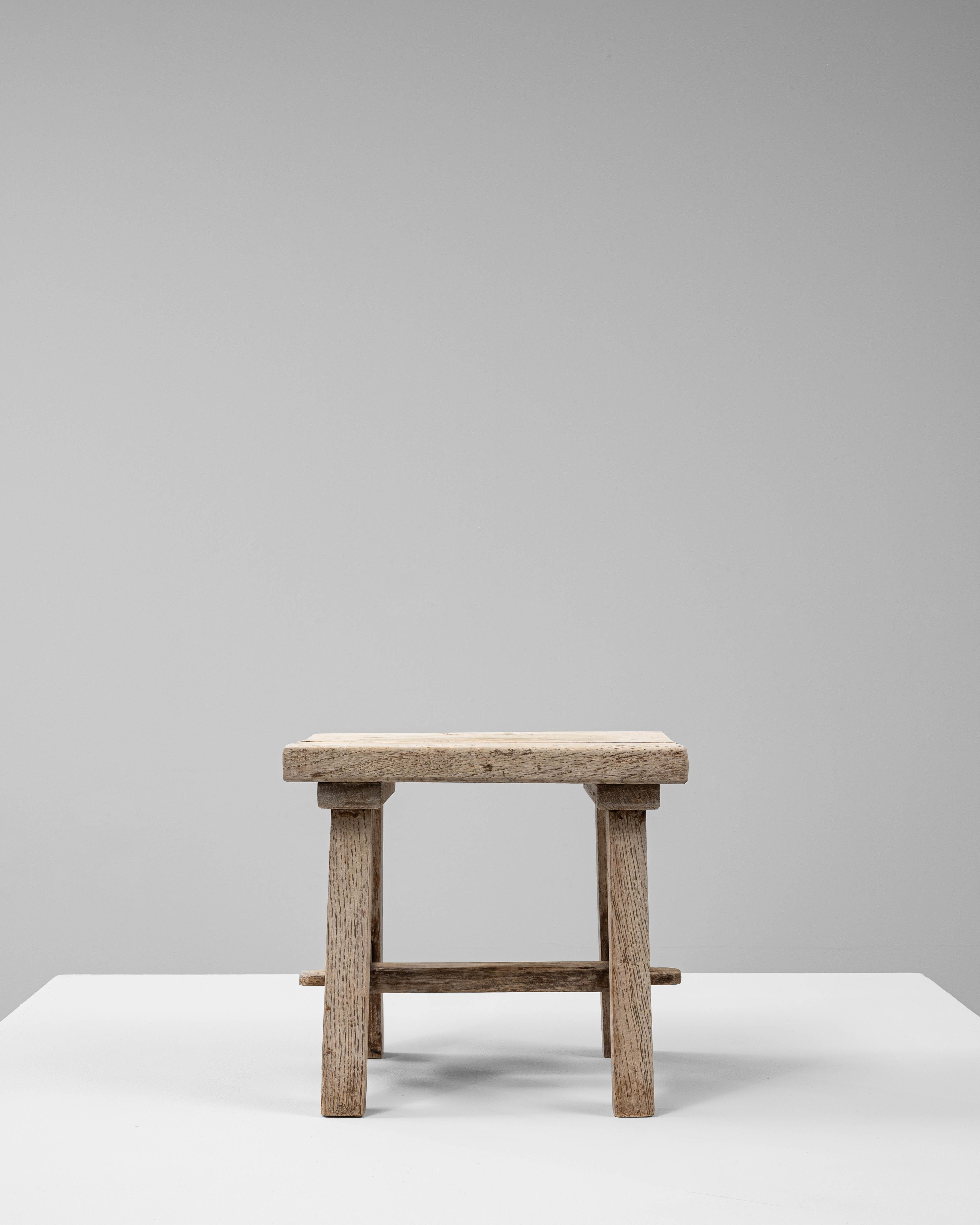 Este pedestal de madera francés del siglo XX destila encanto antiguo por su construcción sencilla y su carácter desgastado por el tiempo. Fabricada en madera maciza, su forma rectangular achaparrada se apoya en cuatro patas cónicas unidas por