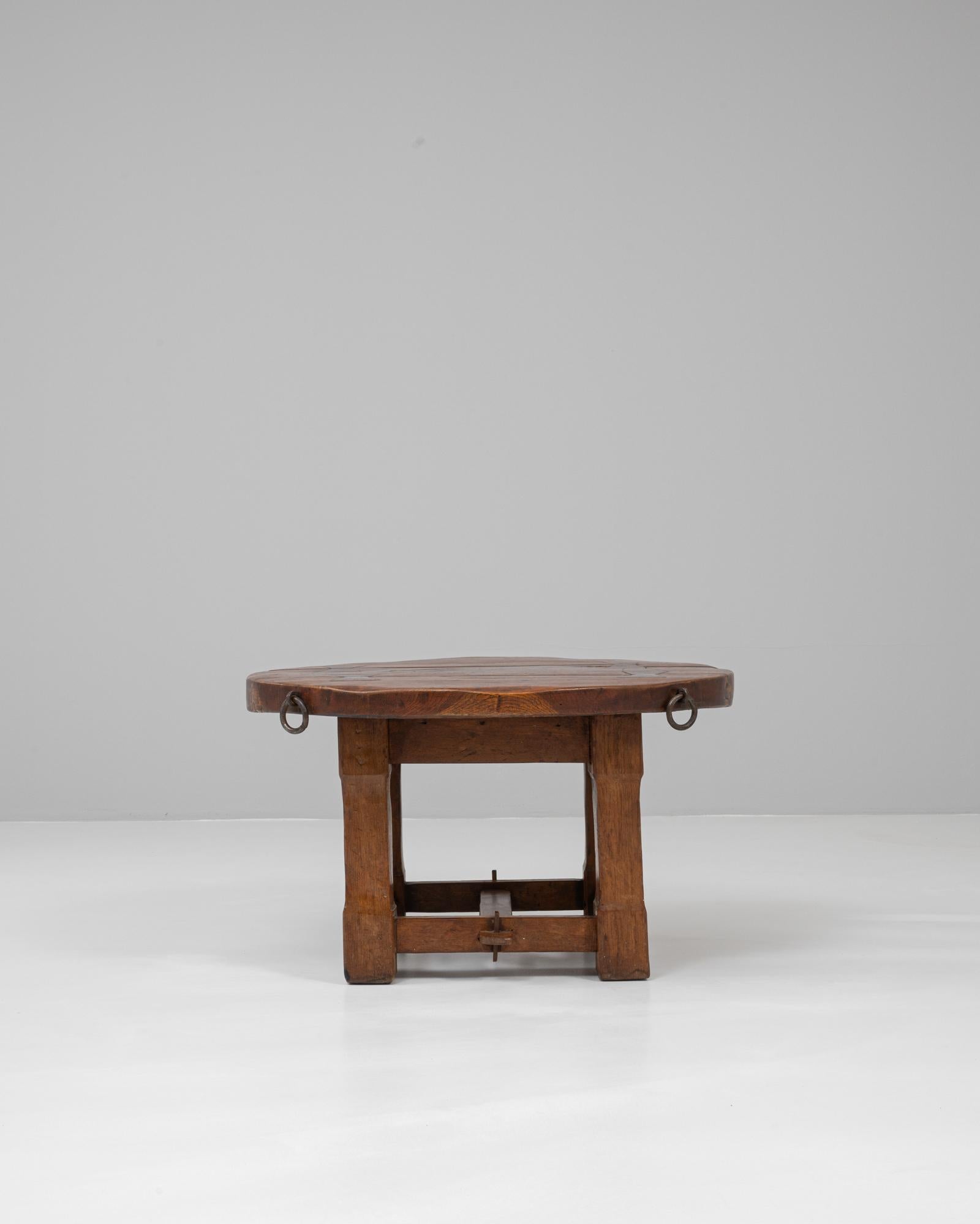 Esta mesa de centro redonda de madera francesa del siglo XX desprende carácter rústico y autenticidad, conservando su pátina original. Hecha a mano con madera maciza, presenta una gruesa encimera circular apoyada en robustas patas unidas con barras