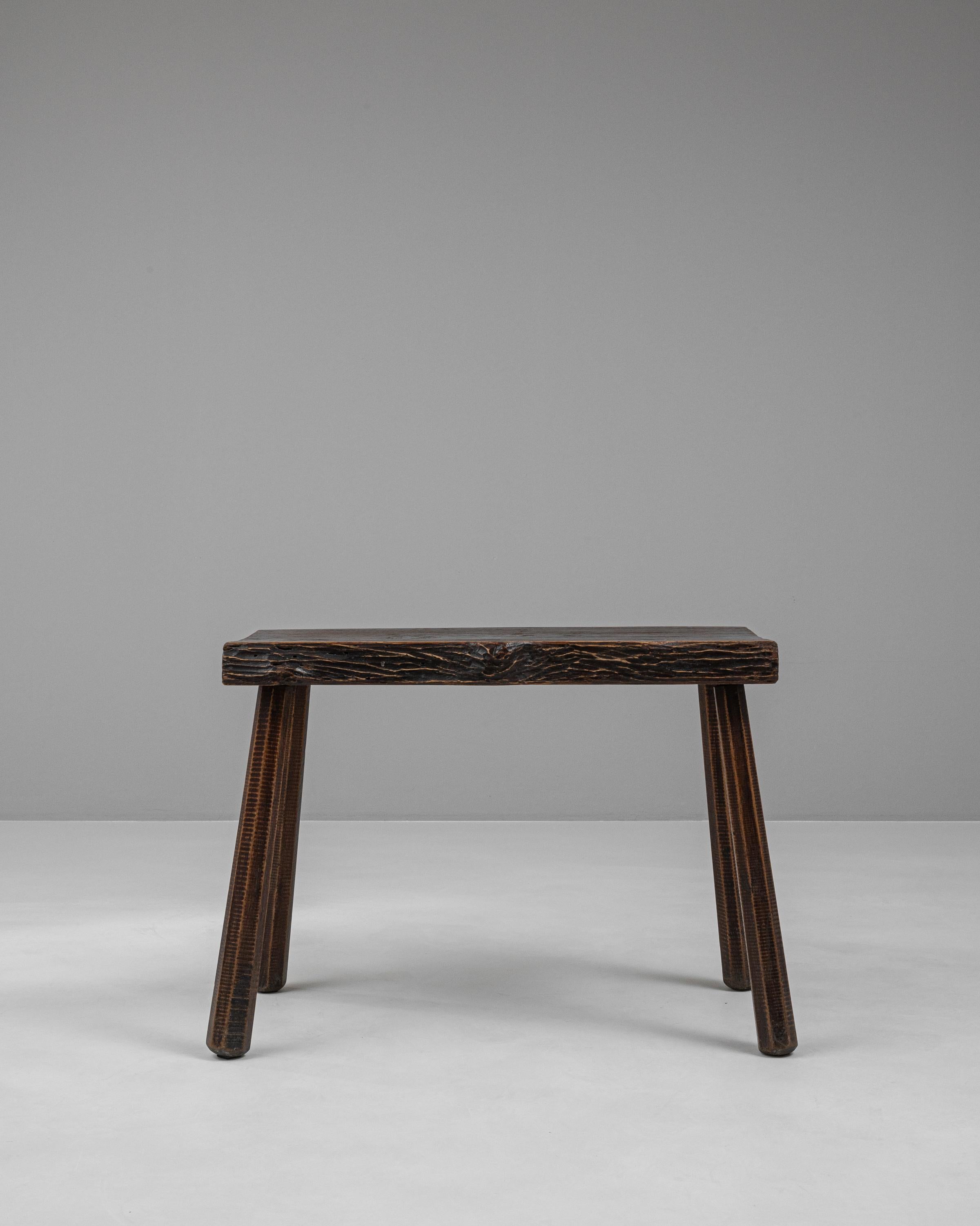 Embrace the rustic allure of this 20th Century French Wooden Side Table, a piece that encapsulates both functionality and the warmth of traditional craftsmanship. This charming side table, with its rich, deep wood tones and distinctive grain