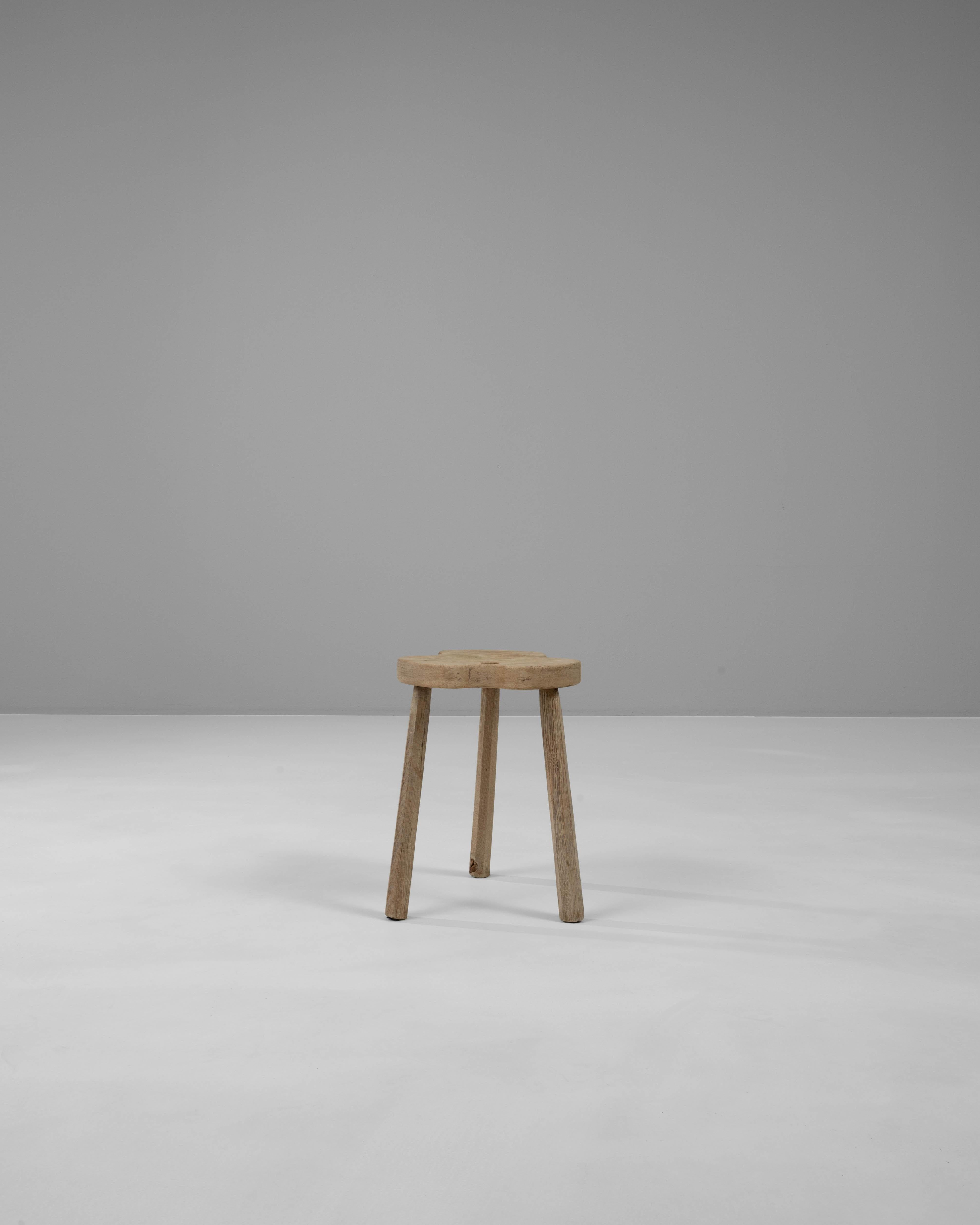 Discover the rustic charm of this 20th Century French Wooden Stool, a blend of minimalist design and utilitarian functionality. Crafted from solid wood, this stool features an organically shaped seat with a distinctive, playful cut-out detail that
