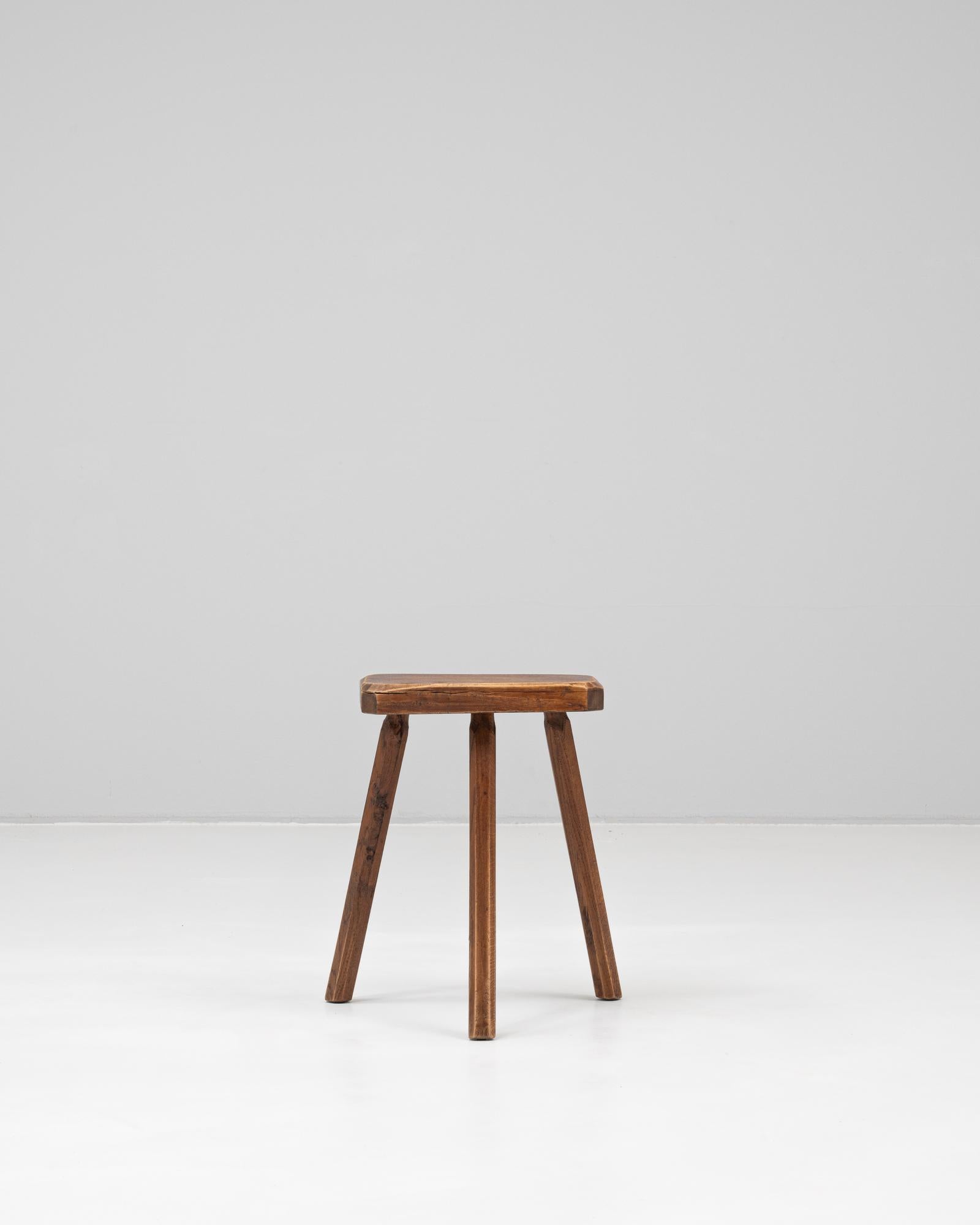 This 20th Century French wooden stool offers a simple yet timeless design rooted in rustic utility and traditional craftsmanship. Constructed from solid wood, the stool features a triangular seat with gently rounded corners and three sturdy,