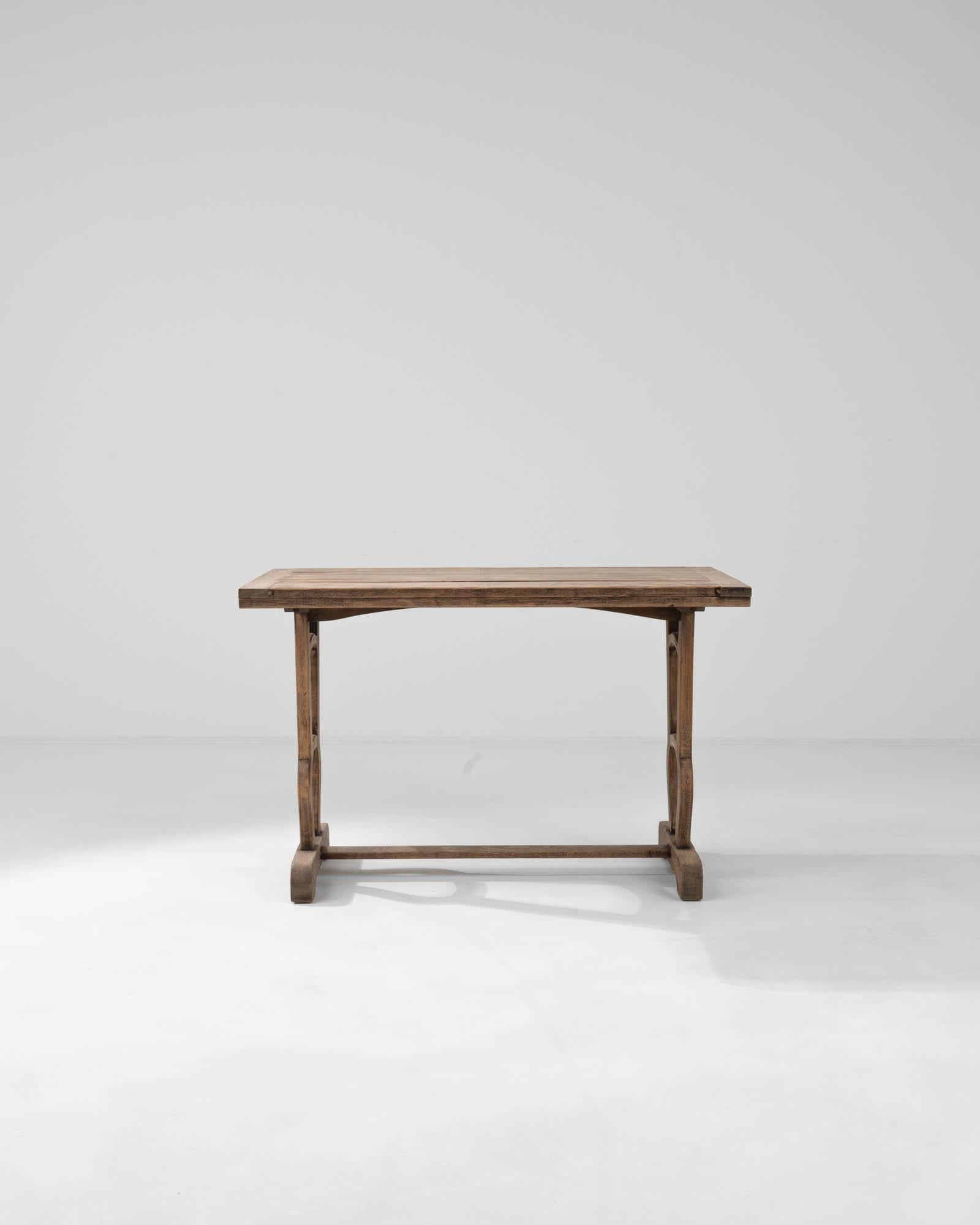 Experience the charm and sophistication of French design with this elegant 20th Century French Wooden Table. Crafted from high-quality wood, this table stands out with its distinctively shaped legs that blend both stability and style, featuring