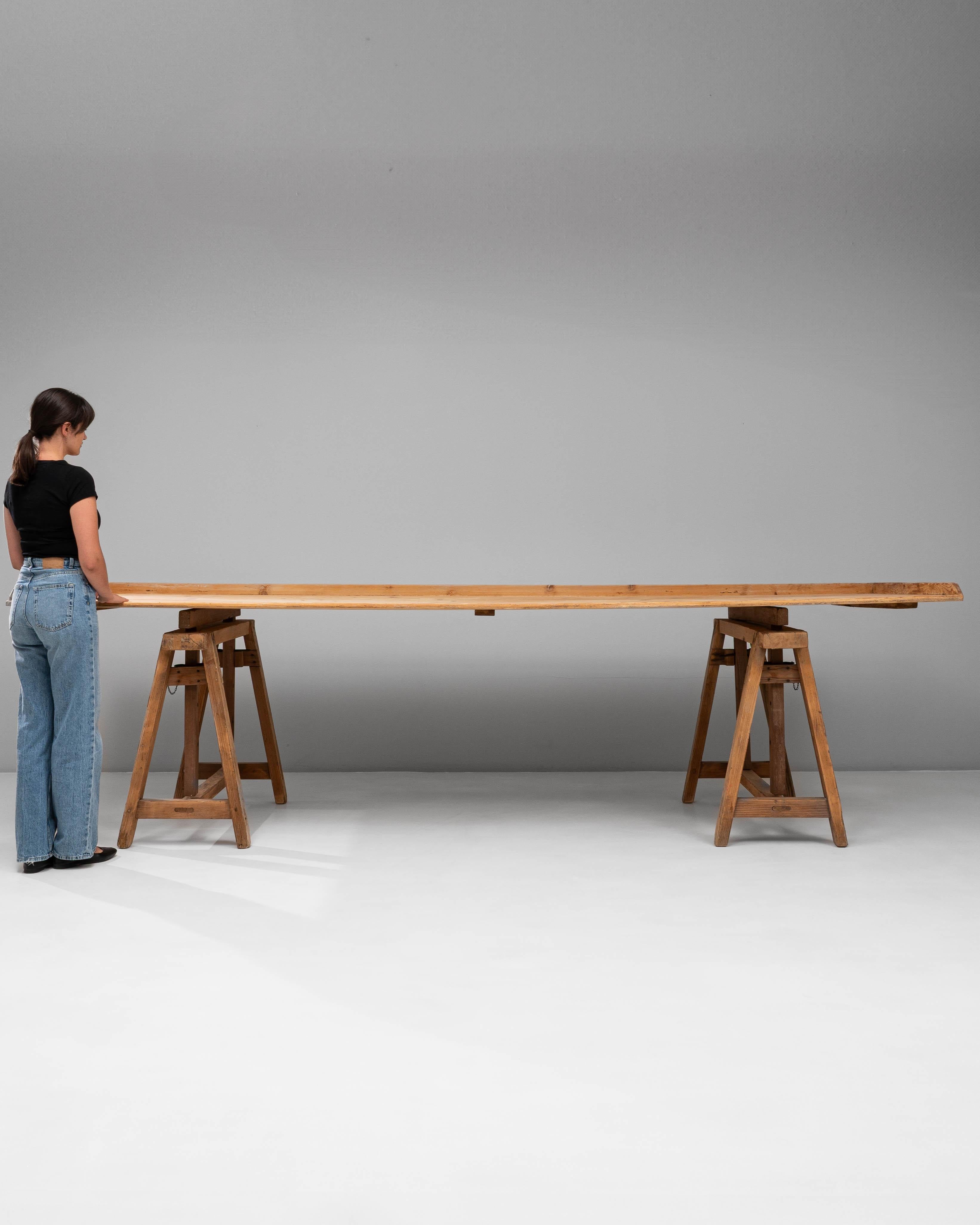 Dieser französische Holztisch aus dem 20. Jahrhundert mit Sägebockfuß verkörpert zweckmäßiges Design, das durch zeitlose Handwerkskunst aufgewertet wird. Der aus Massivholz mit einer warmen, natürlichen Patina gefertigte Tisch hat eine lange,