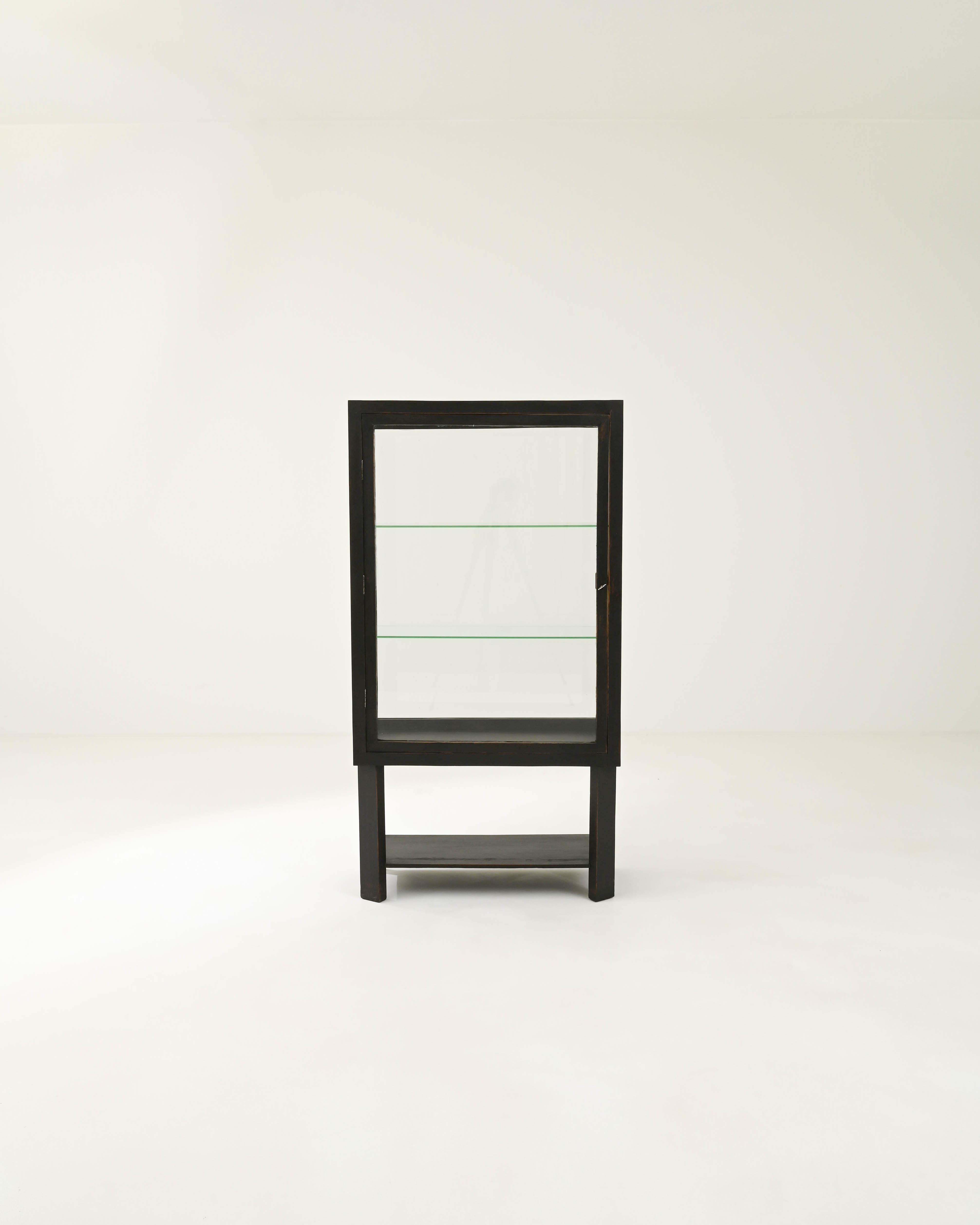 The sleek minimalist design of this vintage wooden vitrine is softened by a subtle patina. Built in France in the 20th century, the stripped-back lines of the cabinet form a bold frame which draws the eye to the objects placed within. Windows on all