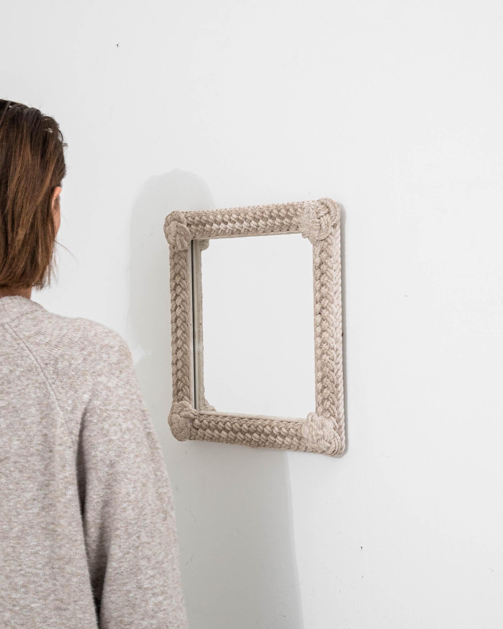 A wooden mirror created in 20th Century France. A truly dazzling work of art, this exquisite mirror exudes a sense of humble regality, articulated effortlessly with a unique motif. The frame of this mirror has been rendered as knotted rope, which
