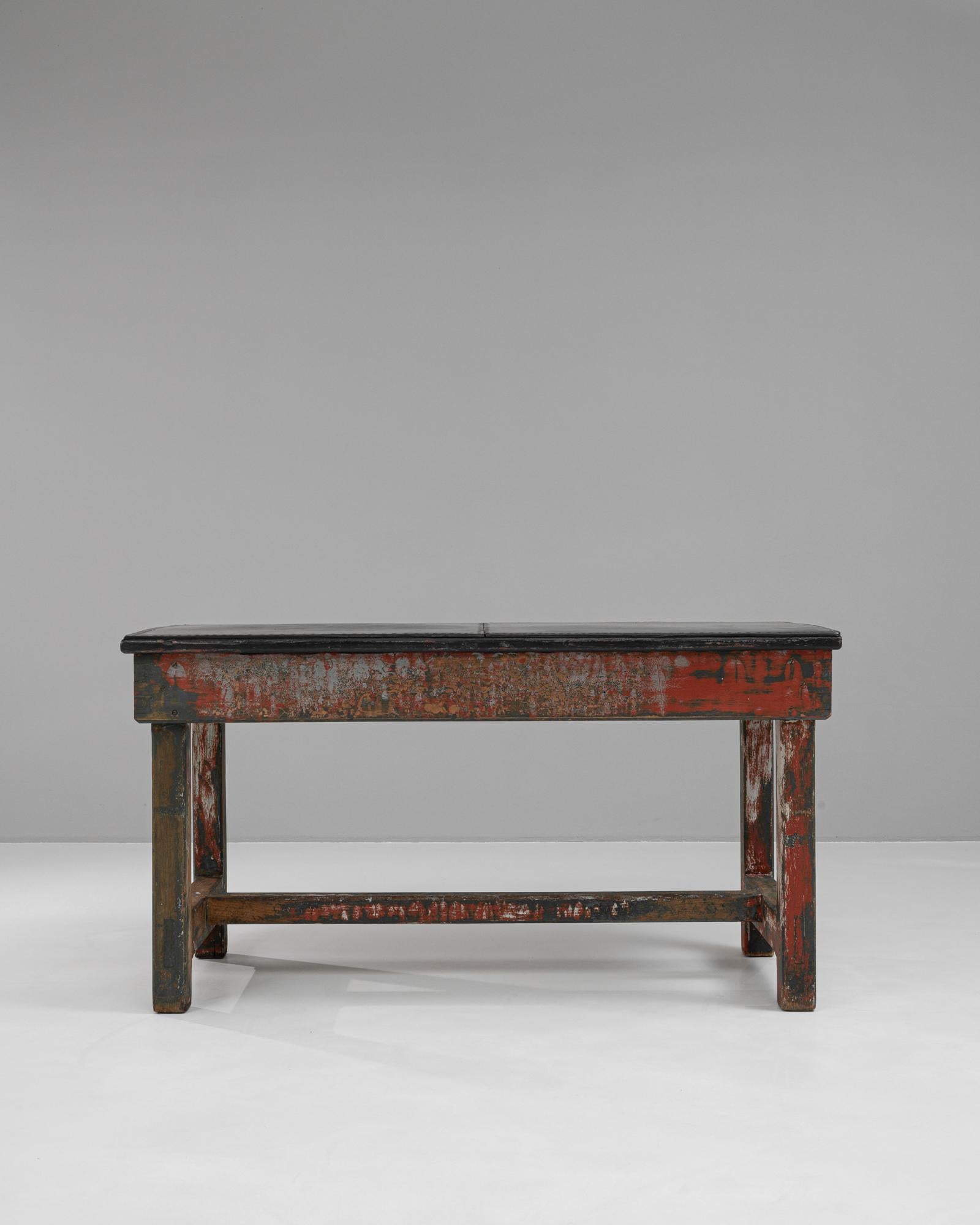 Questo tavolo da lavoro in legno francese del XX secolo è un esempio sorprendente di Rustic Industrial Design, caratterizzato da una finitura ricca di segni di usura con resti di vernice verde e rossa che ne evidenziano il carattere autentico e