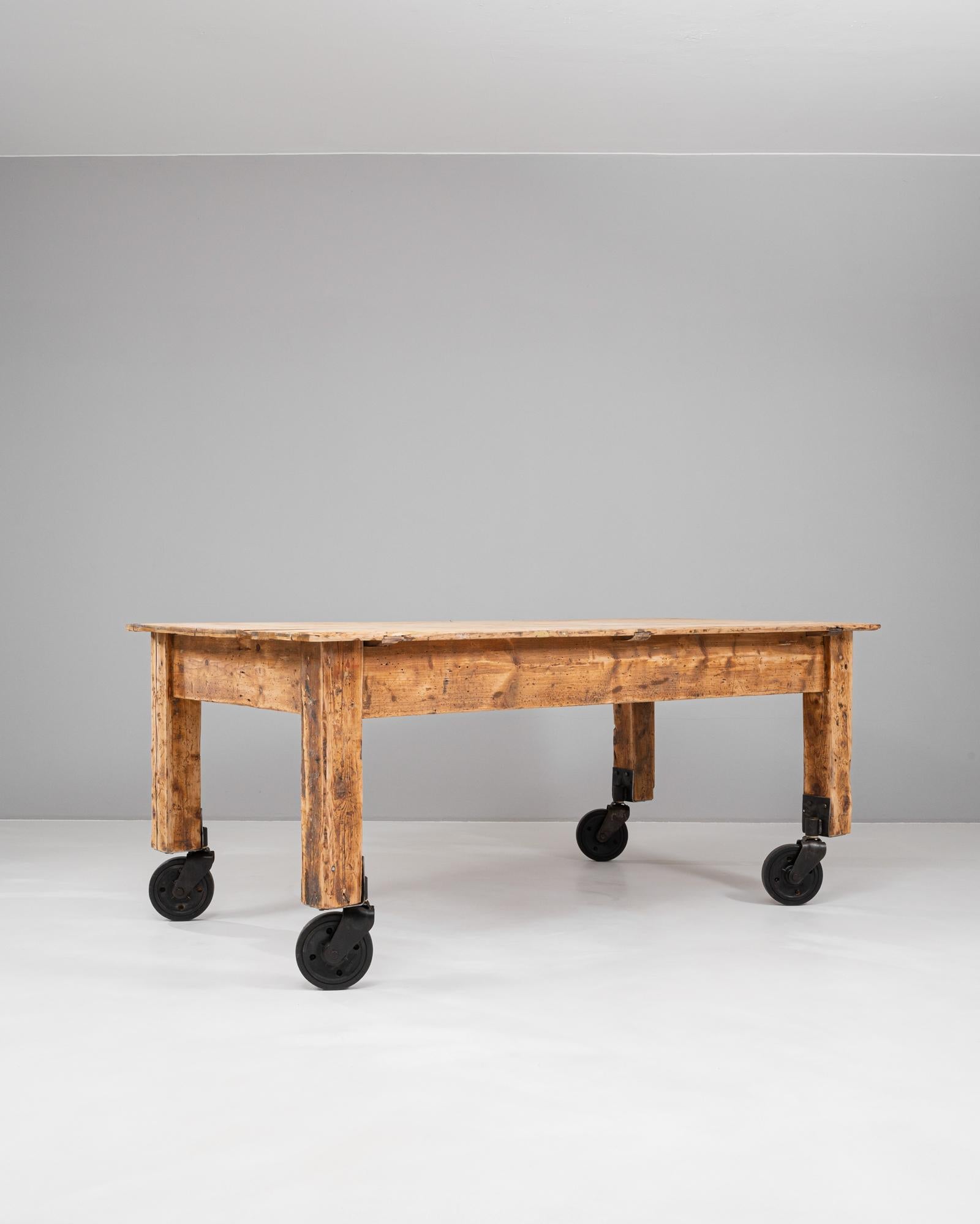 Questo tavolo da lavoro francese del XX secolo combina un fascino rustico con una pratica mobilità, rendendolo un'aggiunta versatile a qualsiasi spazio. Realizzato in legno massiccio, presenta una finitura splendidamente invecchiata che ne evidenzia