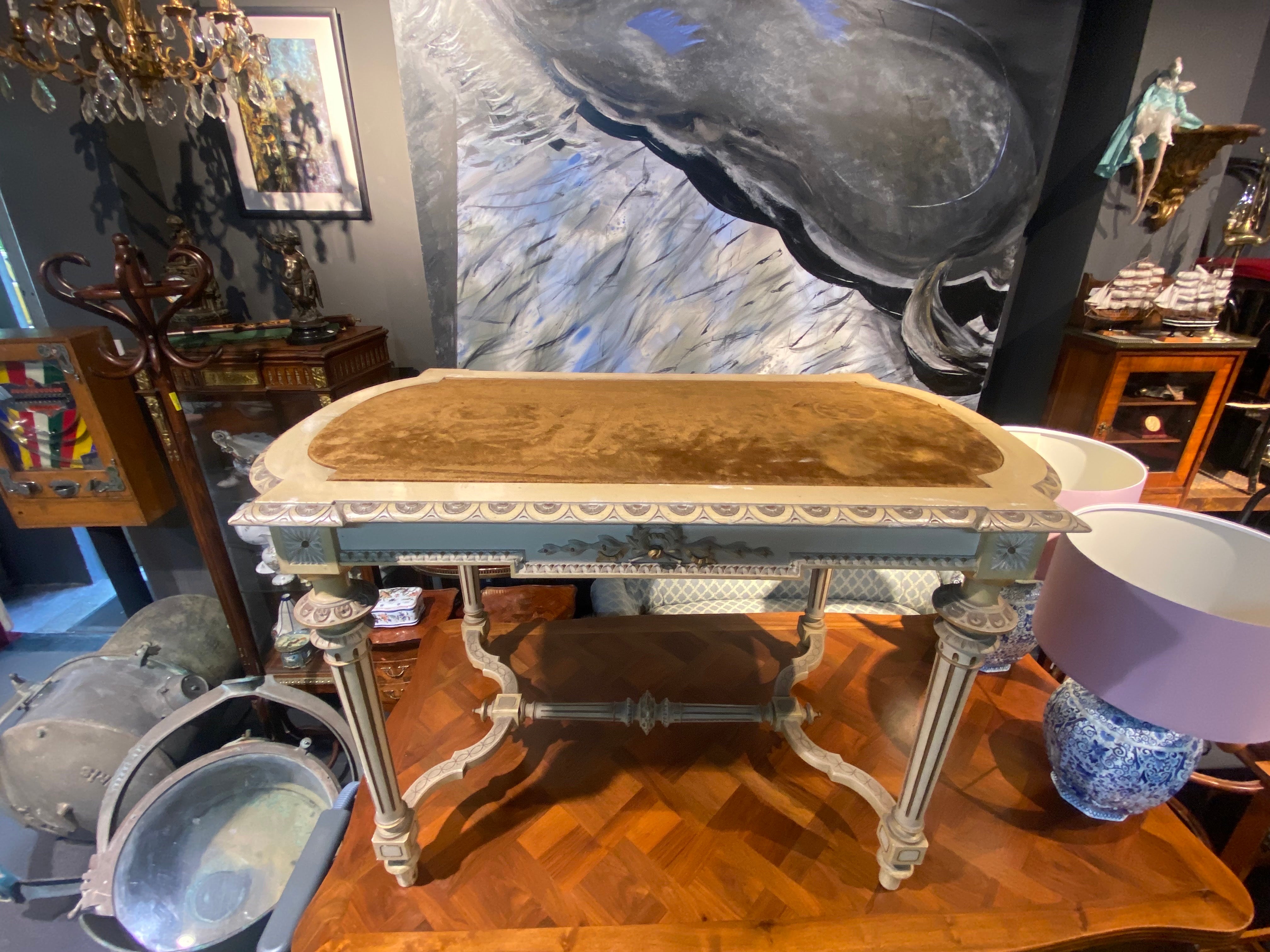 Table en bois français peinte à la main avec plateau en velours cognac. La table est sculptée à la main avec des détails typiques du style Louise XVI comme les rubans en bois doré à l'avant et les pieds cannelés reliés à la base. Tous les détails