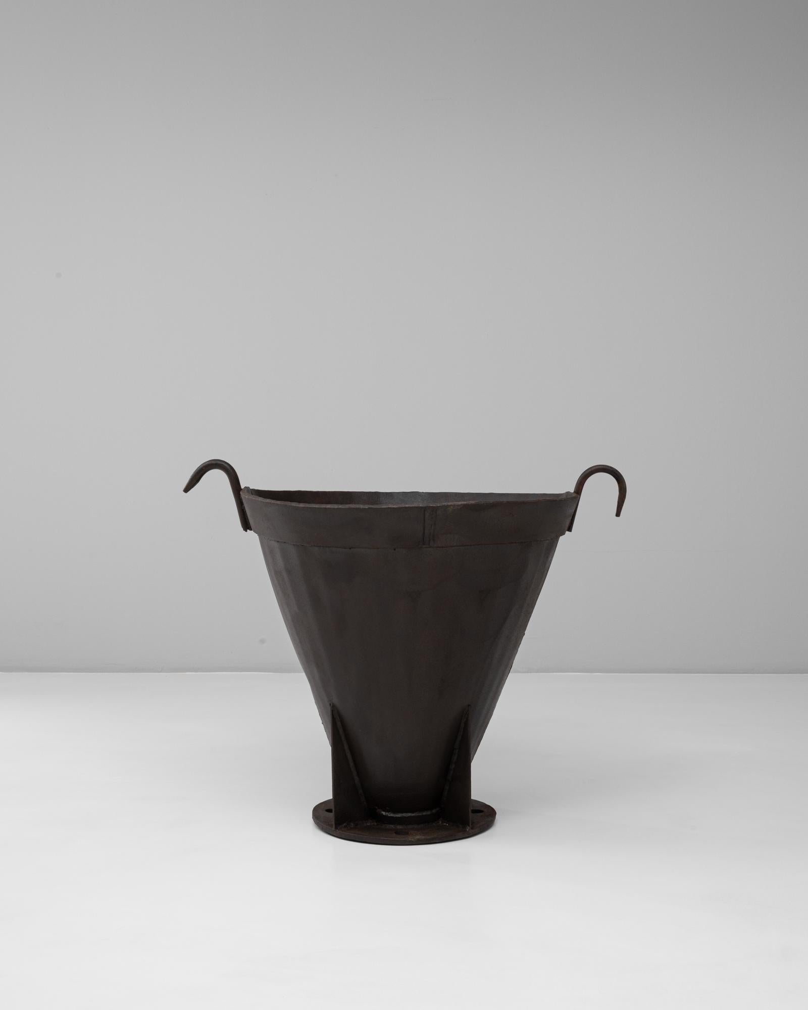 Cette cheminée à urne évasée en fer forgé français du 20e siècle incarne la force industrielle avec une silhouette sculpturale. Fabriqué avec un corps conique effilé, il repose sur une base circulaire robuste et présente des poignées audacieuses et