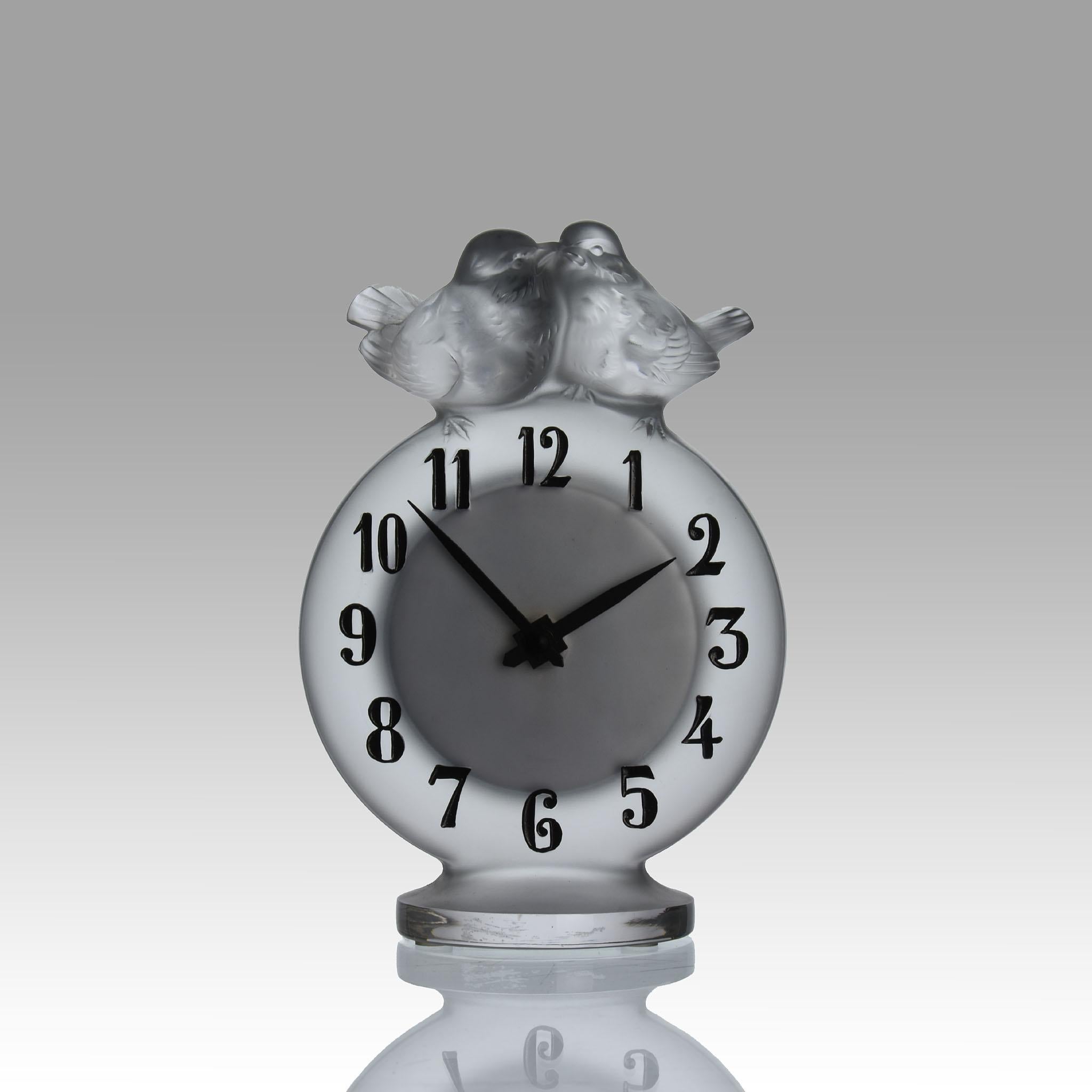 Ravissante horloge française en verre dépoli surmontée de deux tourtereaux perchés, le cadran avec des chiffres en émail noir, signée Lalique France.

INFORMATIONS COMPLÉMENTAIRES
Hauteur :                                       15 cm
Largeur :      