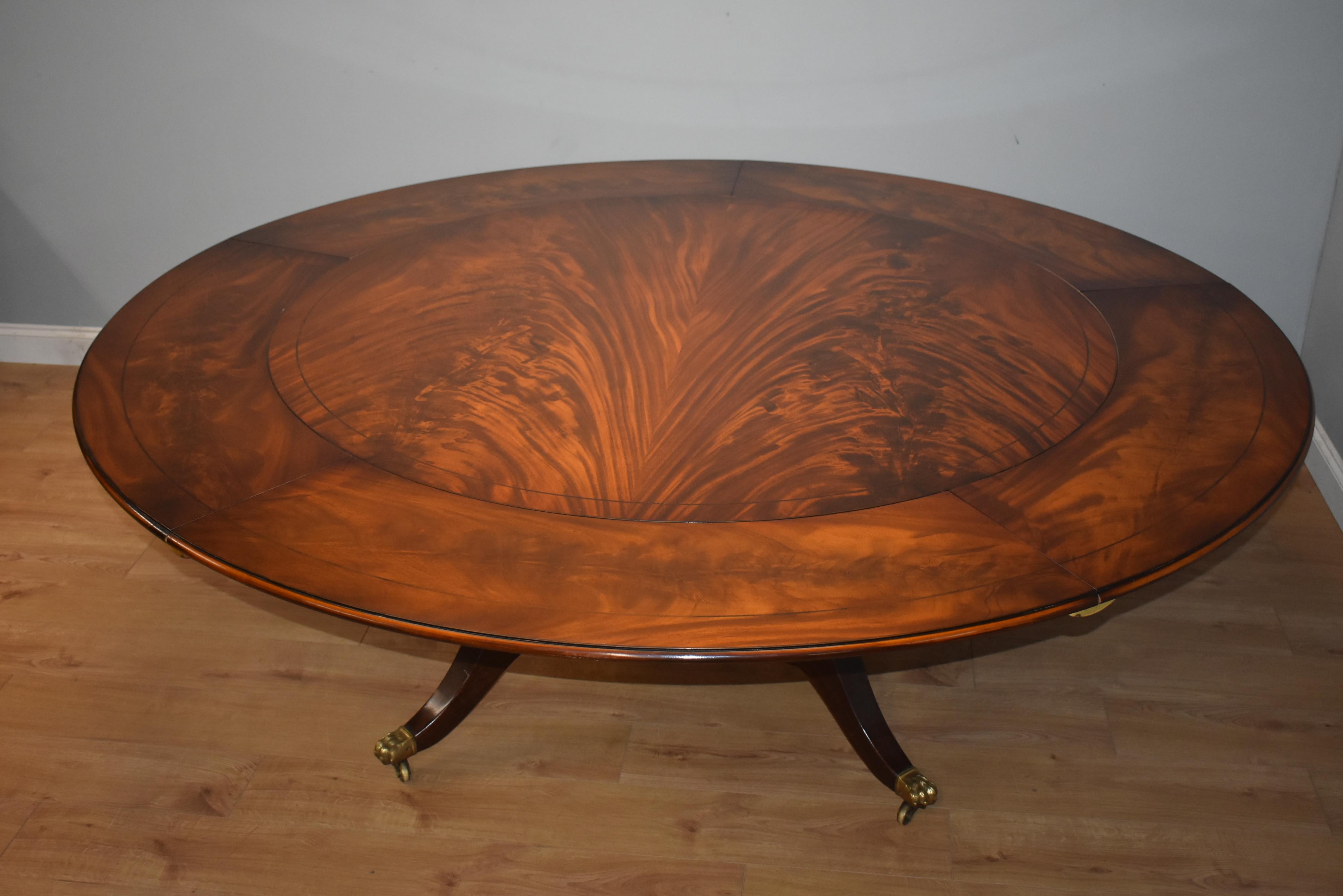 For sale is a fine quality George III style mahogany Jupe table. The circular top, veneered in beautiful flame mahogany has five additional leaves, allowing the table to extend to seat 12 people. Each leaf is also veneered in superbly figured