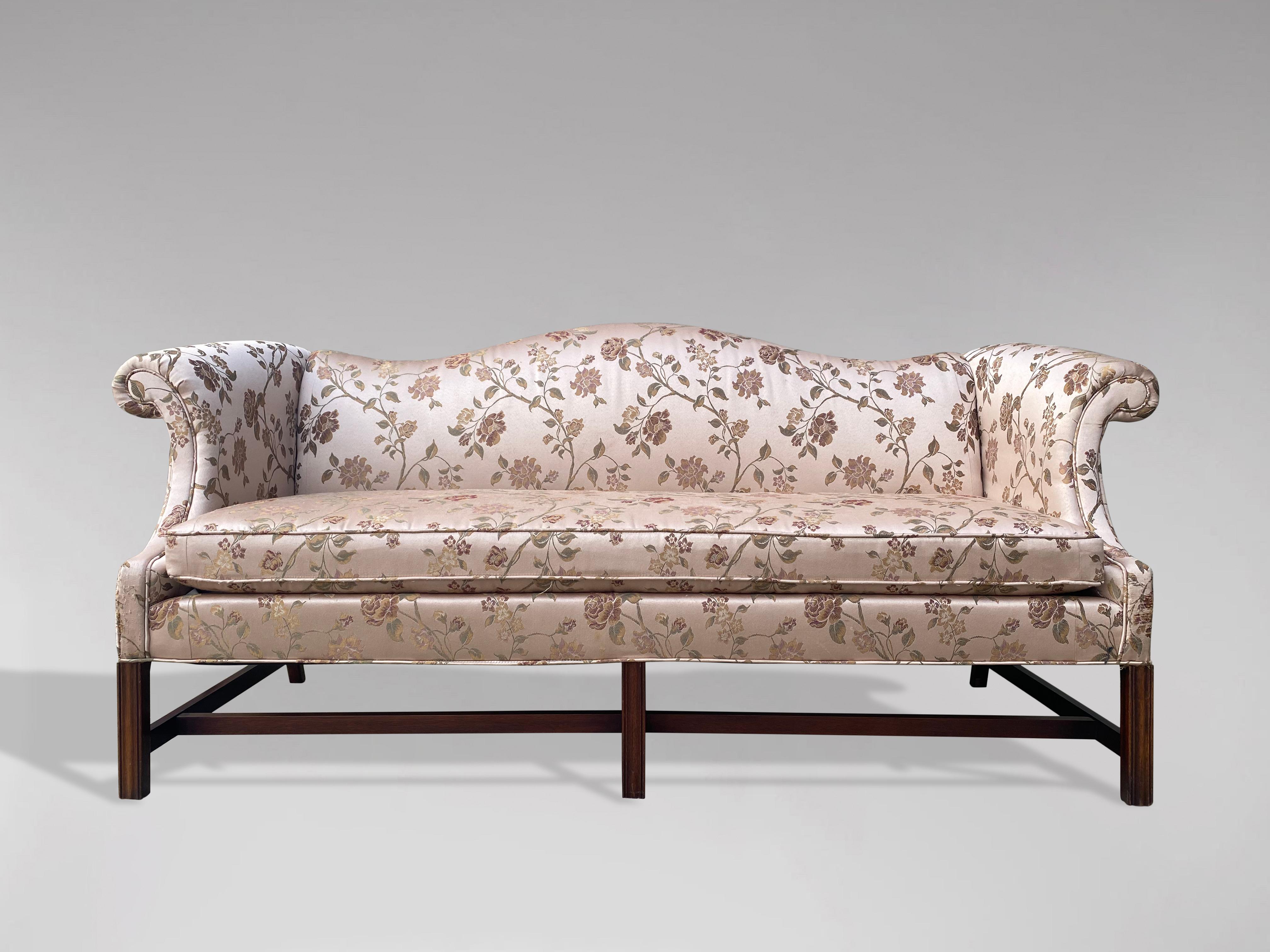 An elegant 20th century, George III style, upholstered humpback sofa. Finely upholstered with outscrolling arms raised over three moulded front legs and two back legs with a lovely sweep to them, supported by distinctive stretchers. Very comfortable