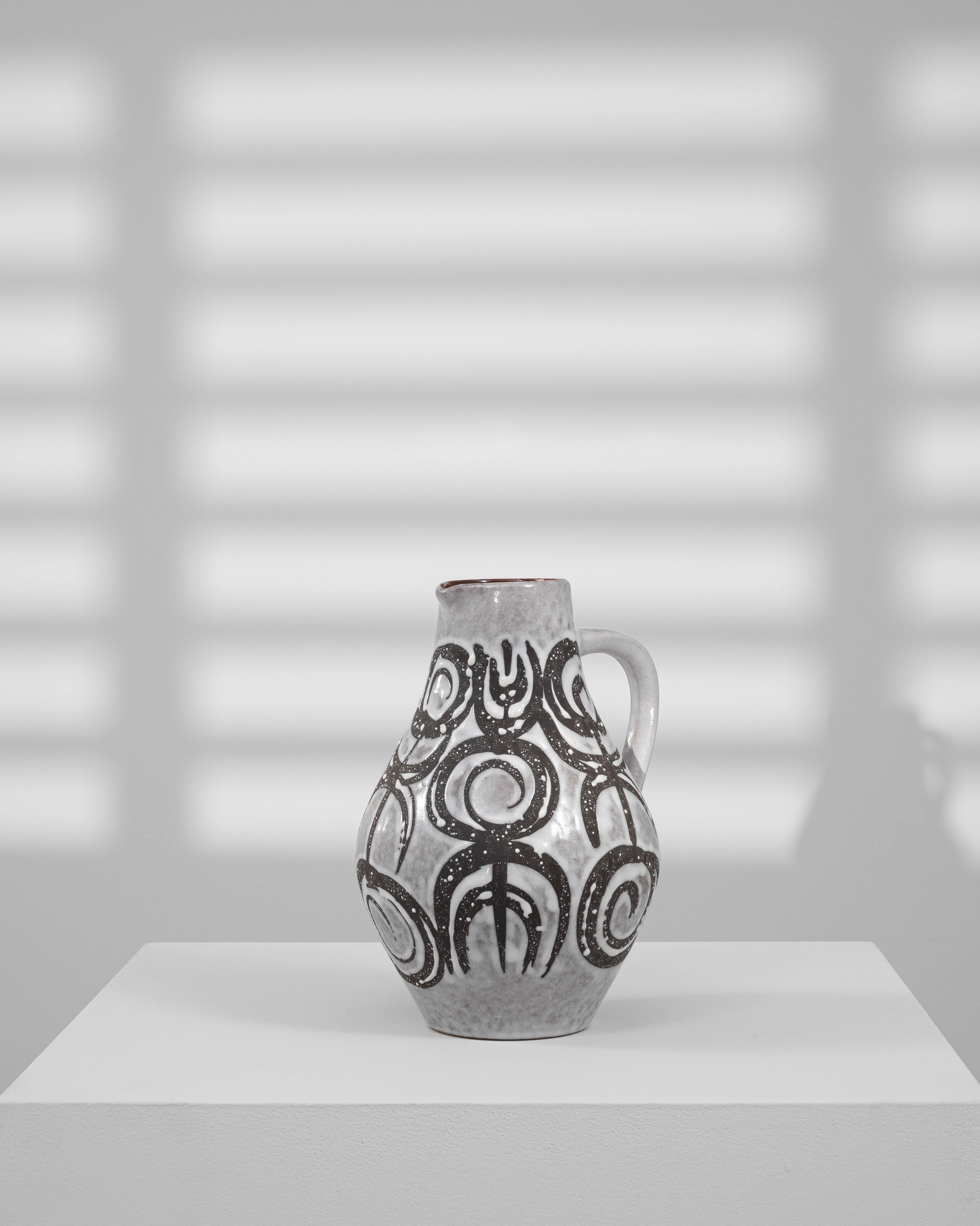 Brocca in ceramica tedesca del XX secolo dalla forma scultorea e arrotondata con manico curvo e un sorprendente motivo astratto nero su uno smalto grigio tenue. I motivi circolari e lineari dipinti a mano evocano lo stile espressivo caratteristico