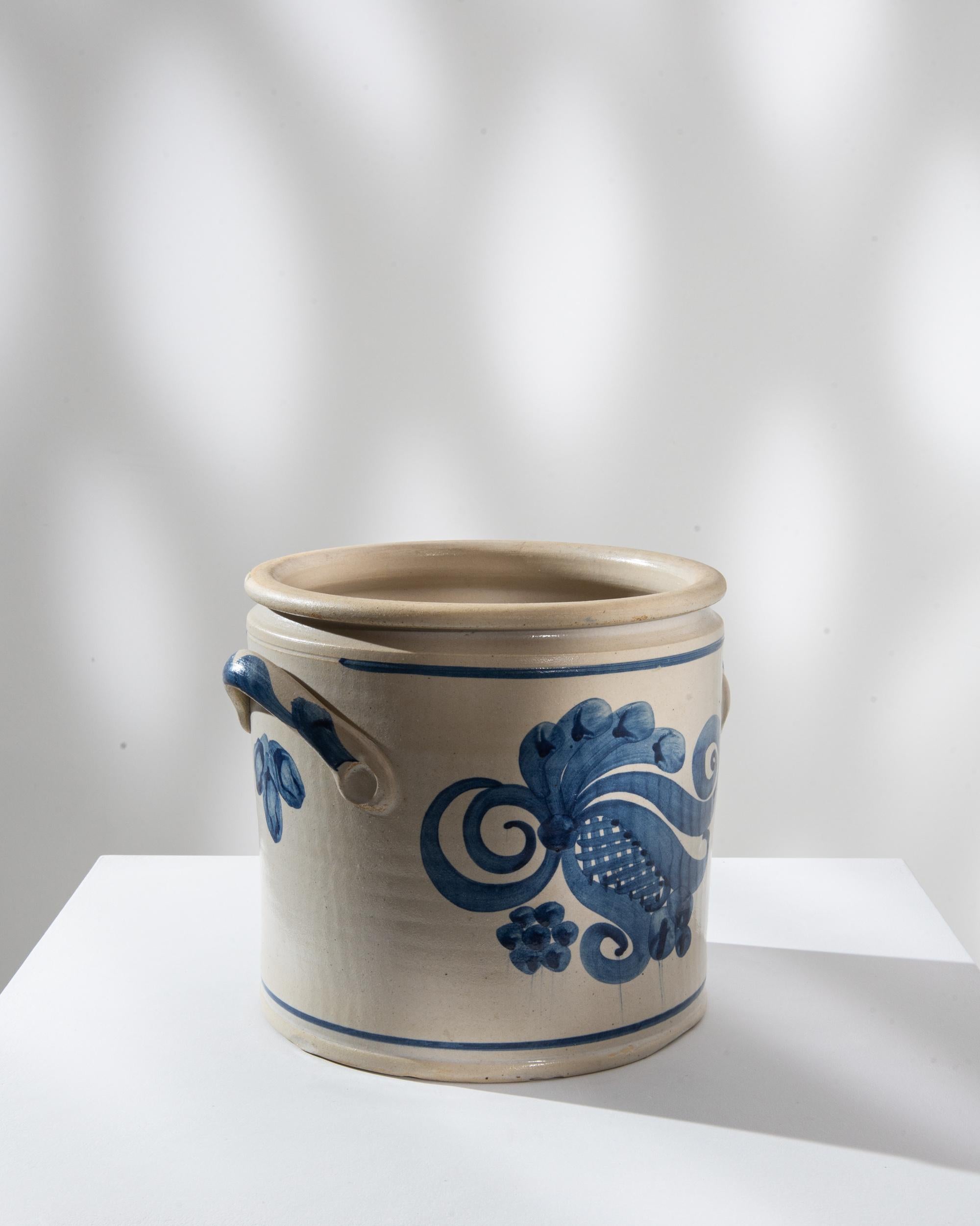 Rehaussez votre décor avec cet exquis pot en céramique allemand du XXe siècle, qui témoigne d'un savoir-faire intemporel. Le pot présente une base blanc crème ornée de motifs floraux bleus complexes, dégageant un air d'élégance et de sophistication.