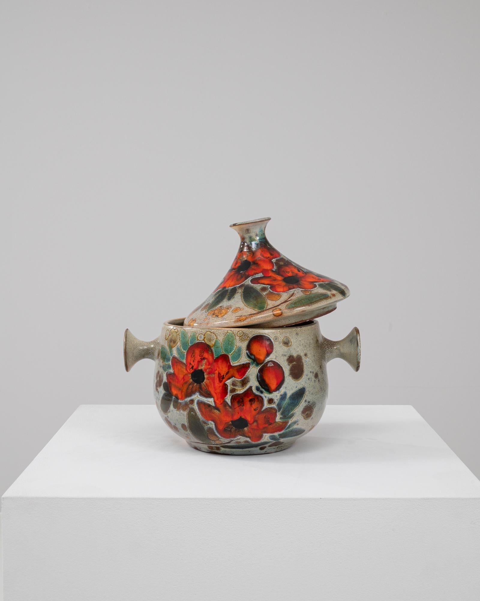 Questo affascinante vaso in ceramica tedesca del XX secolo con coperchio è un delizioso mix di funzionalità ed espressione artistica. Caratterizzato da un disegno dipinto a mano di vivaci fiori rossi e fogliame verde, questo pezzo irradia calore e