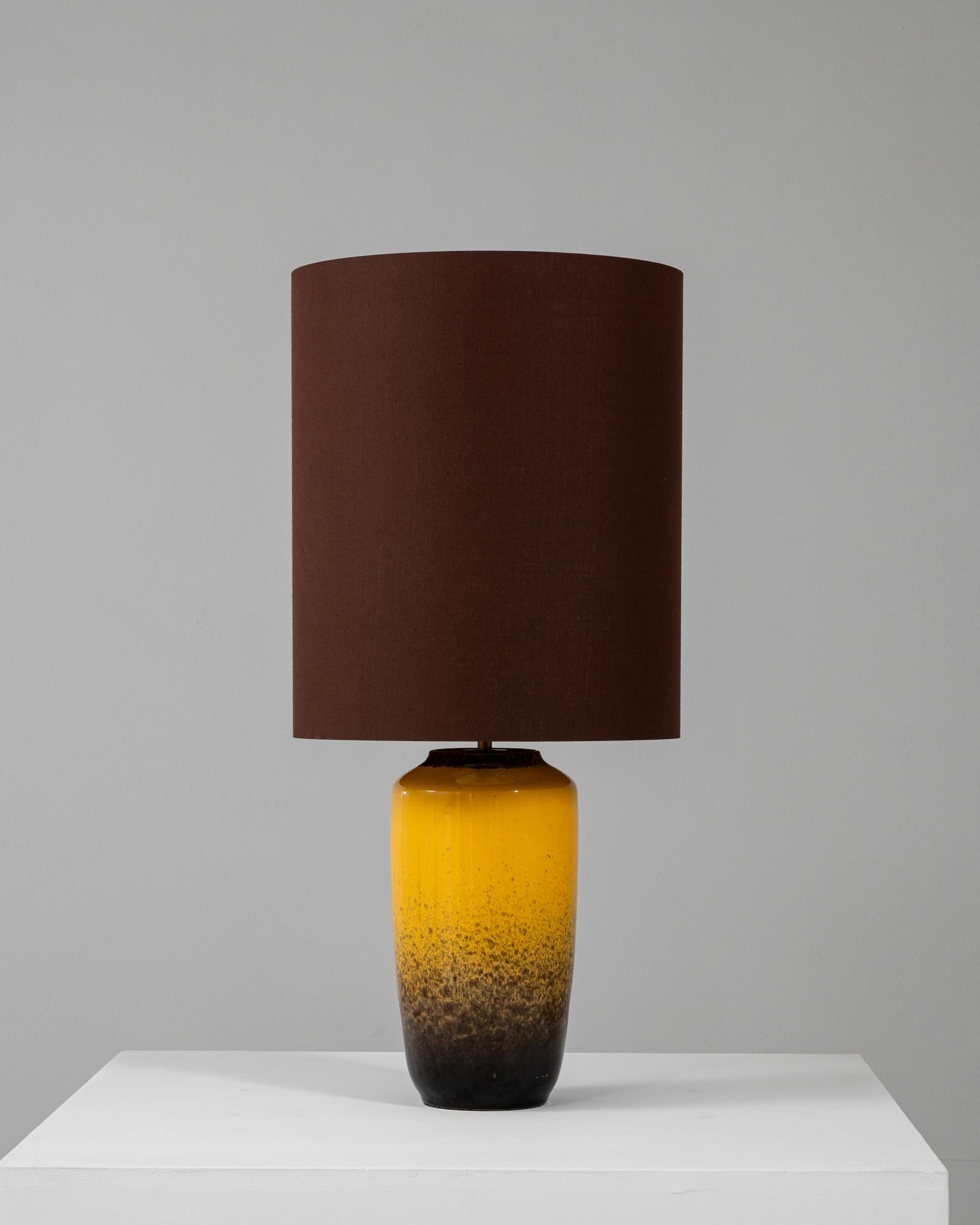 Cette lampe de table en céramique allemande du XXe siècle est un mélange parfait de charme vintage et d'attrait moderne. La base jaune vibrante présente un motif dégradé qui passe à un noir profond dans la partie inférieure, créant un look dynamique