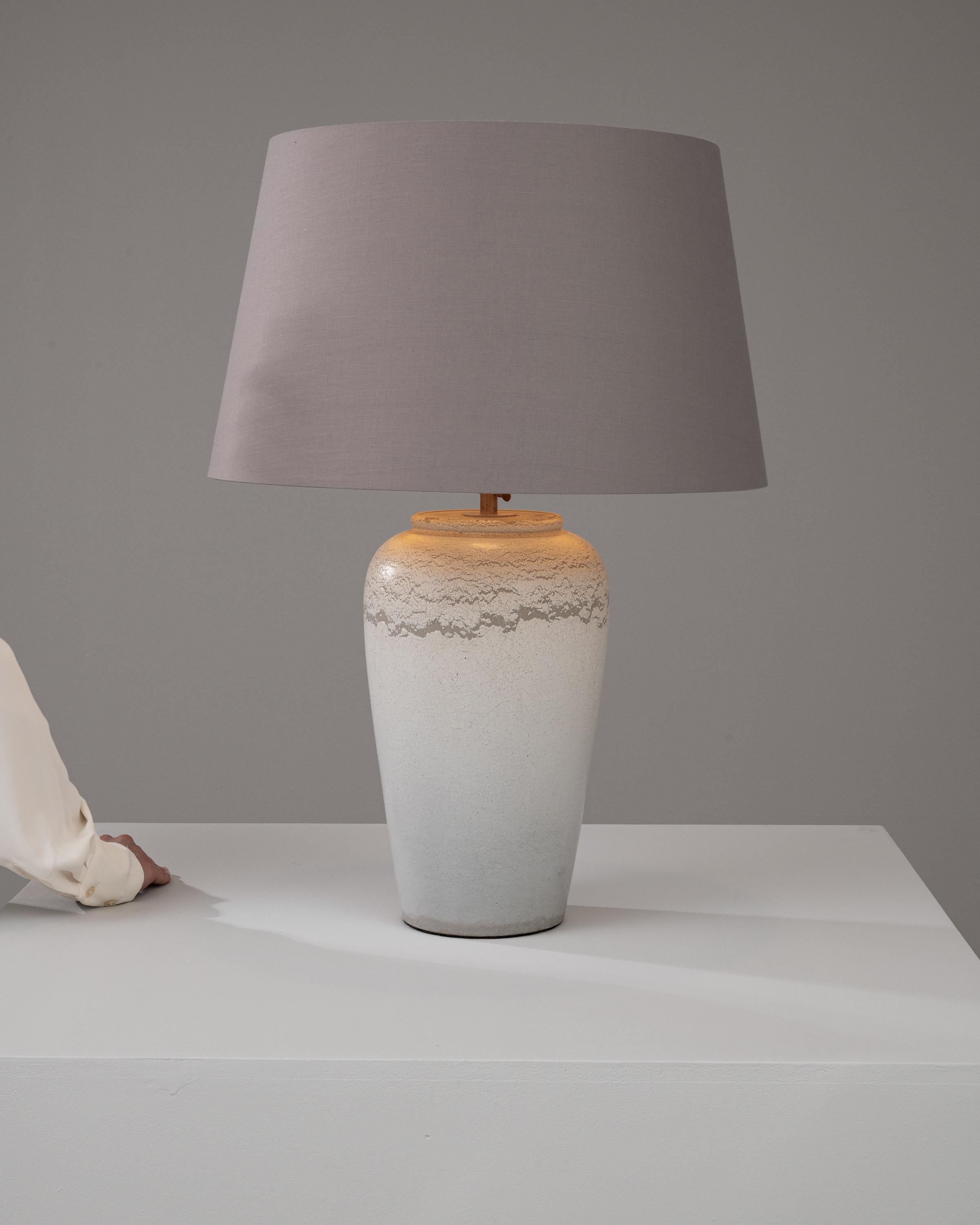 Illuminate your home with this exquisite 20th Century German Ceramic Table Lamp, a testament to timeless design and expert craftsmanship. The lamp’s body is a stunning study in contrasts, featuring a textured, frosted ceramic finish that beautifully