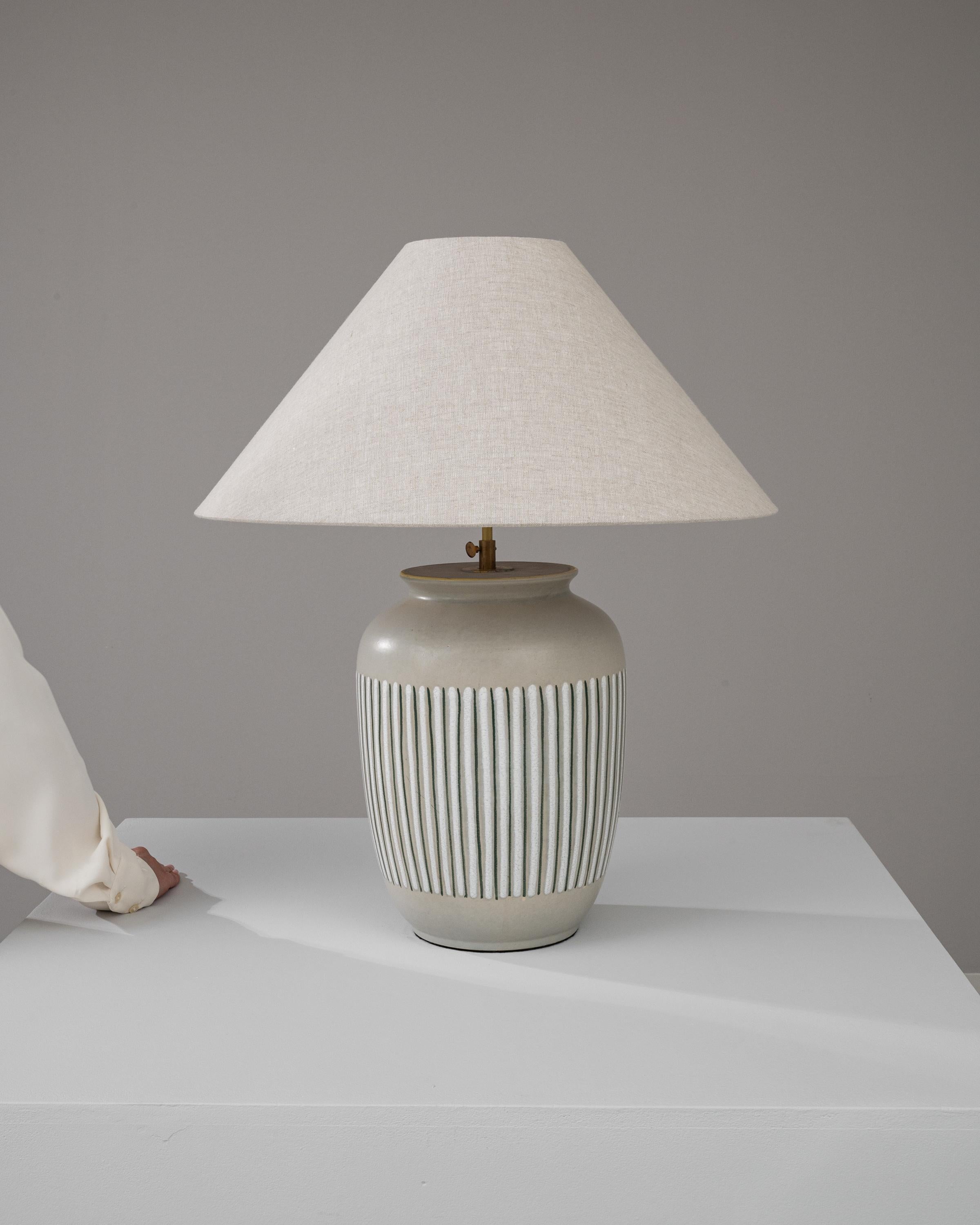 Illuminate your space with the timeless elegance of this 20th Century German Ceramic Table Lamp, a testament to classic design and craftsmanship. The lamp's body is a harmonious blend of form and function, featuring a robust ceramic base adorned