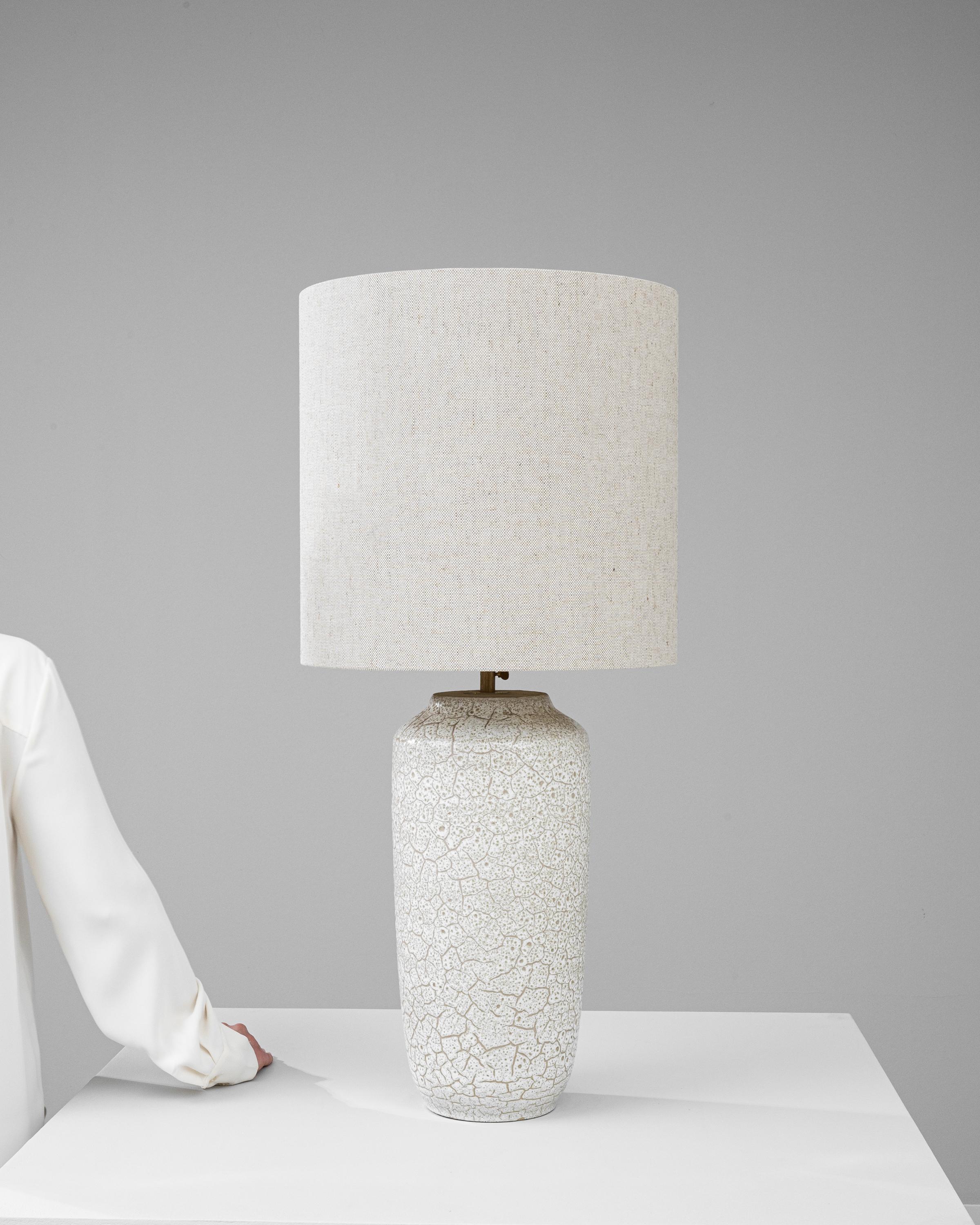 Bask in the delicate intricacy of this 20th Century German Ceramic Table Lamp, a piece that masterfully blends art and functionality. The lamp's surface is a canvas of crackled texture, resembling a fine mosaic of frost on a winter's day, creating