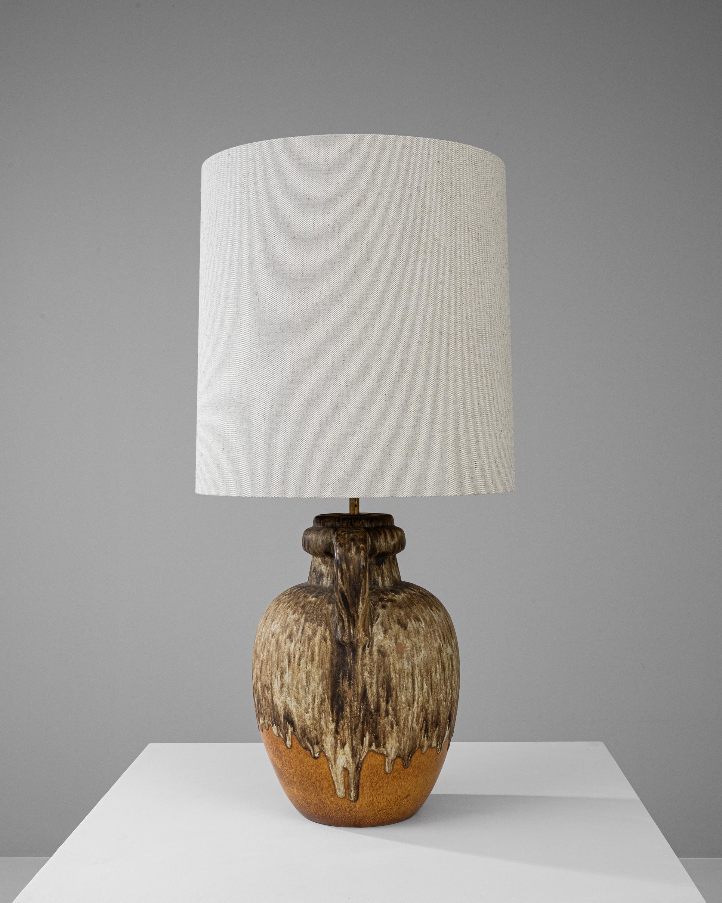 Immerse in the organic allure of this 20th Century German Ceramic Table Lamp, where natural inspiration meets handcrafted design. The base, reminiscent of a gourd picked straight from the vine, features a textural cascade that mimics molten lava