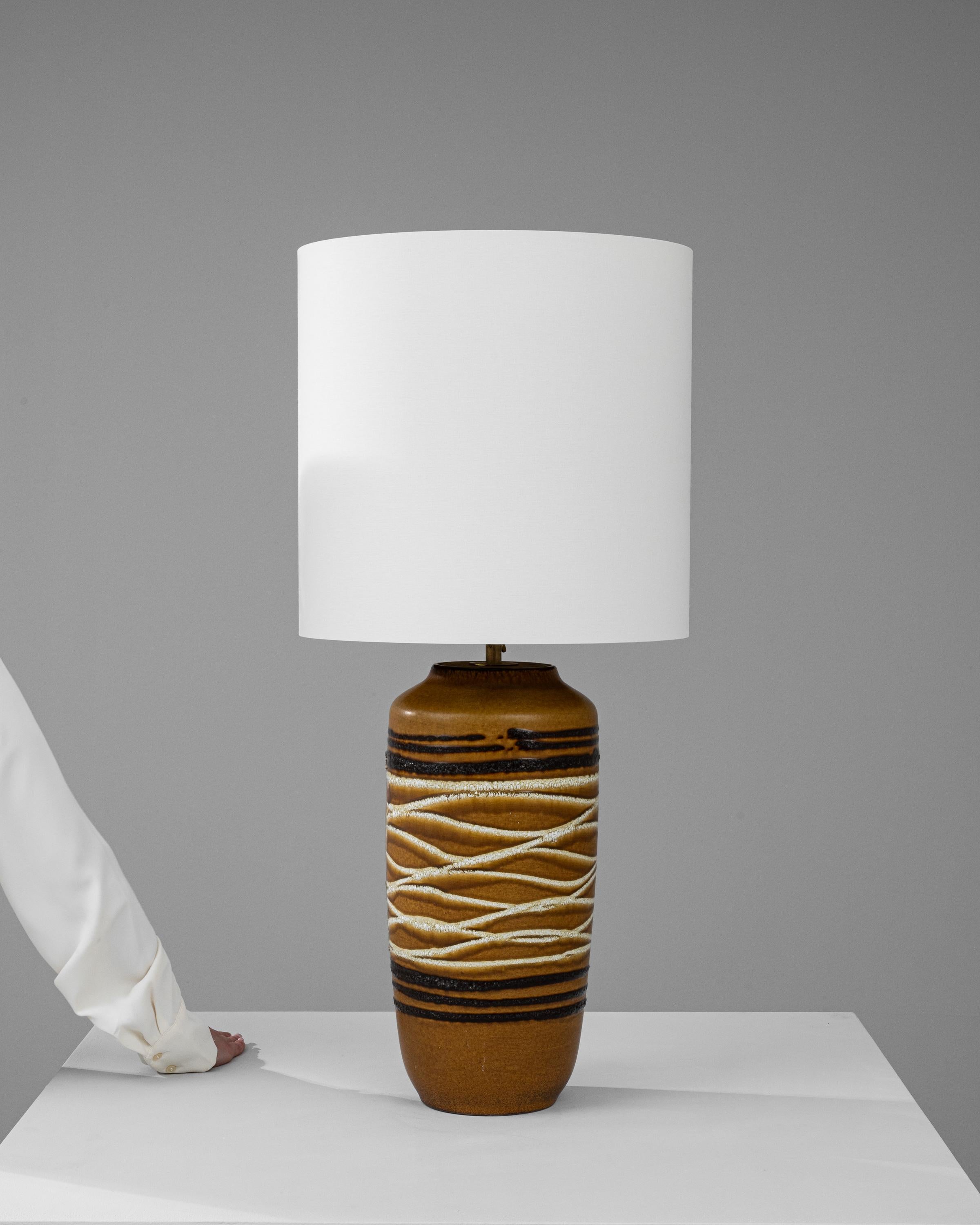 Step into a world of tactile intrigue with this 20th Century German Ceramic Table Lamp, a delightful fusion of traditional craftsmanship and rustic design. The lamp's base is adorned with a tactile motif of rope-like textures, wrapped around its
