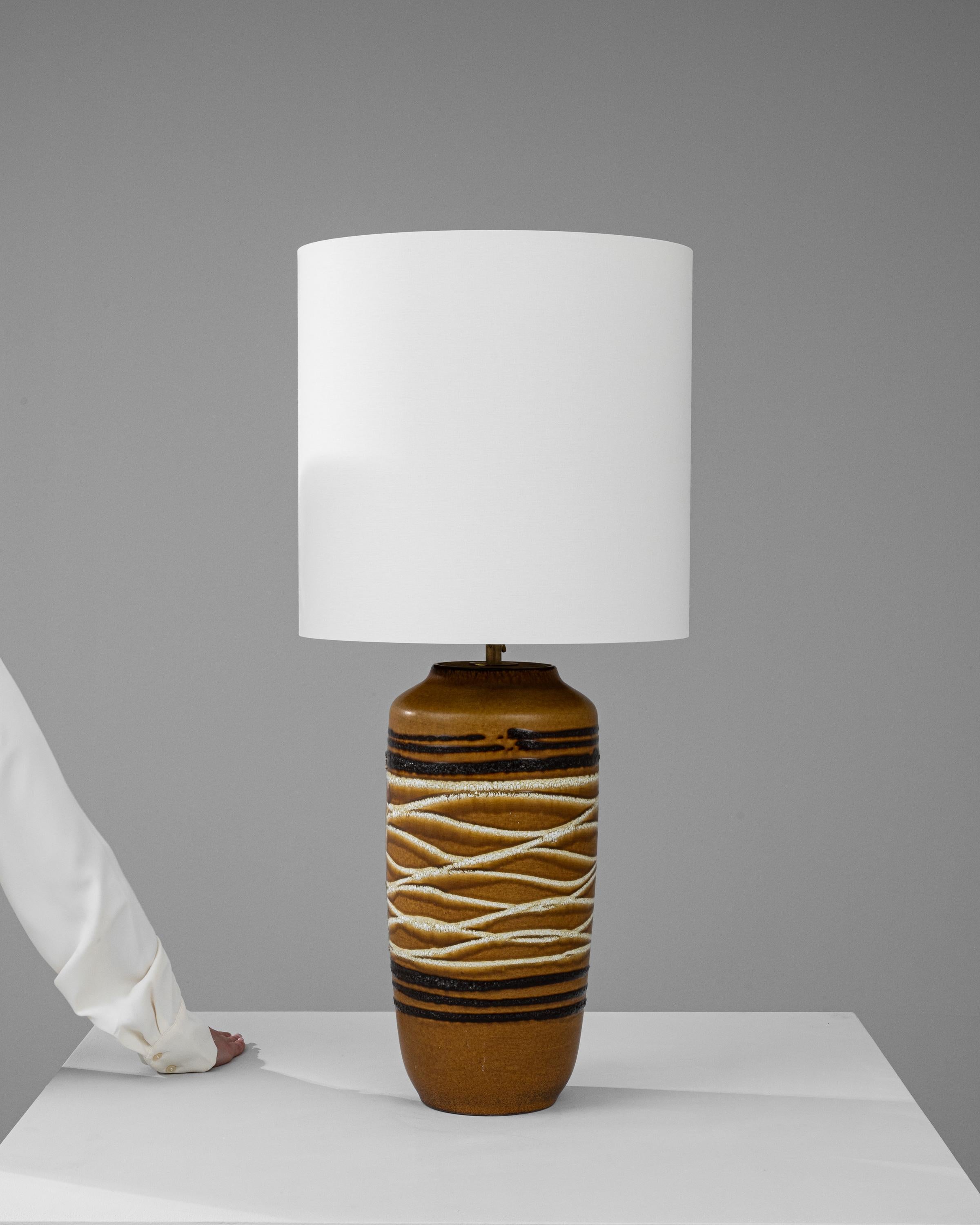Entrez dans un monde d'intrigues tactiles avec cette lampe à poser en céramique allemande du XXe siècle, une délicieuse fusion d'artisanat traditionnel et de design rustique. La base de la lampe est ornée d'un motif tactile de textures semblables à
