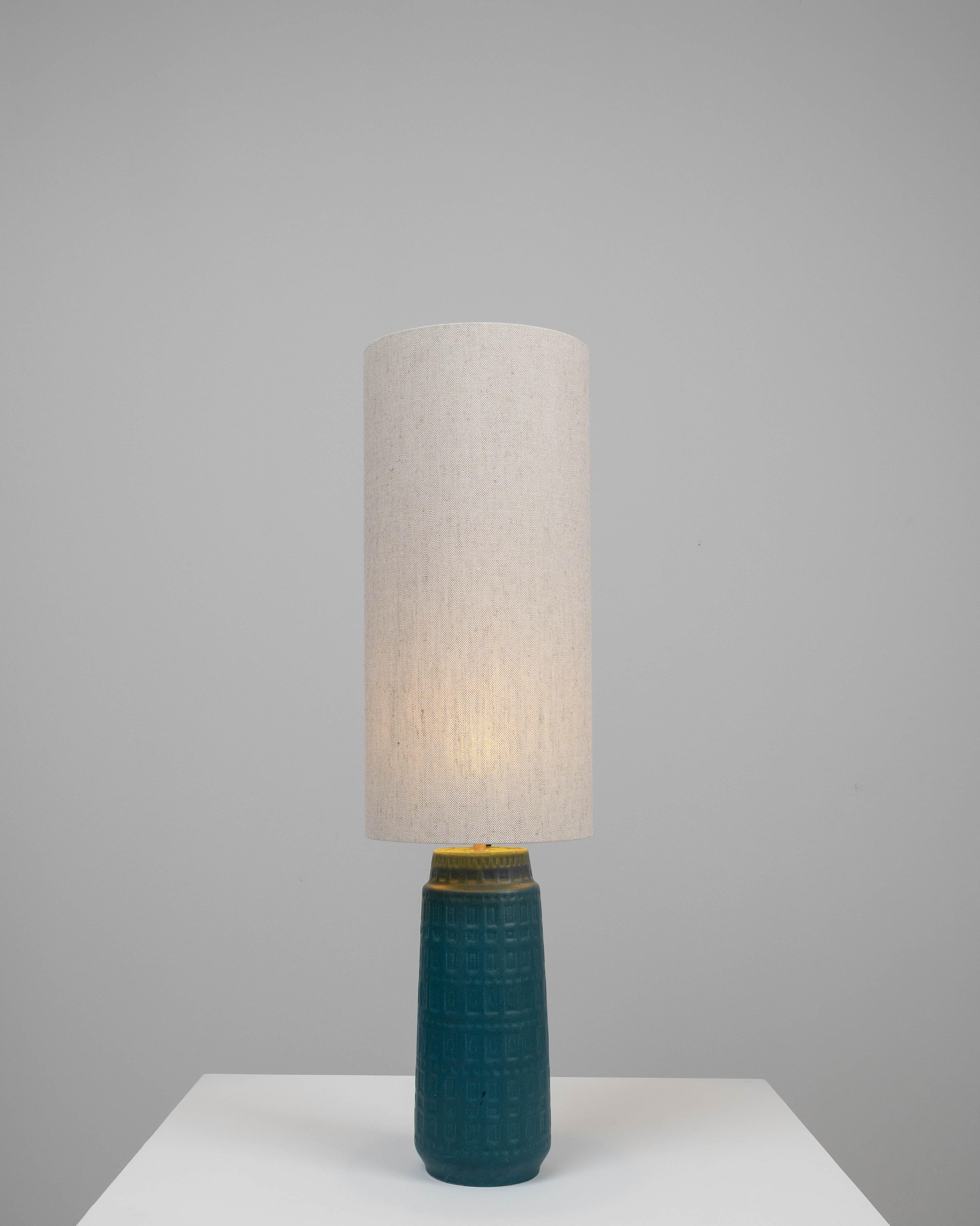 This 20th-century German ceramic table lamp showcases the timeless beauty of craftsmanship with its deep blue hue and embossed geometric patterns. The base of the lamp is a ceramic work of art, featuring a rich, textured design that captures the eye