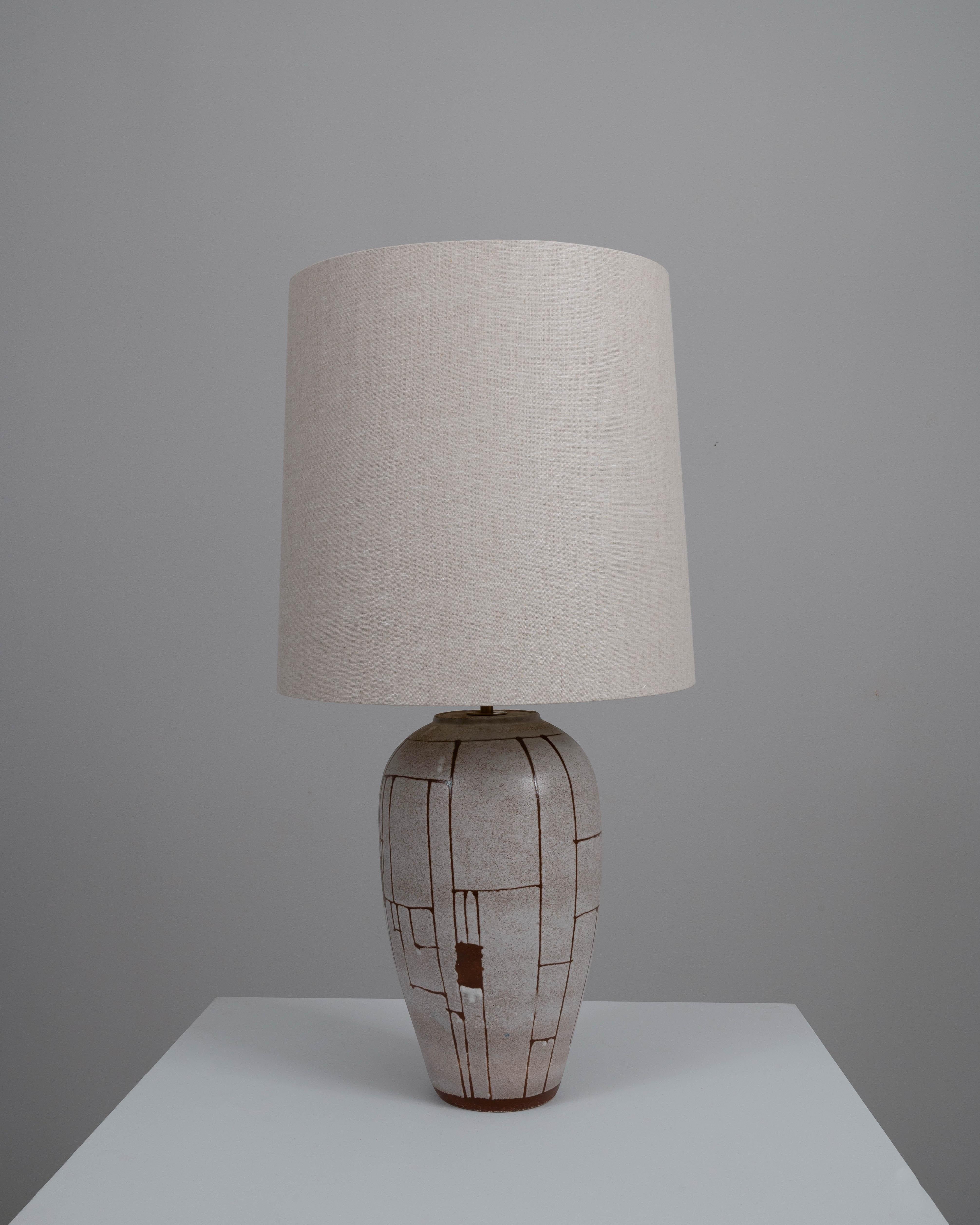 Elevate your home decor with this exquisite 20th-century German ceramic table lamp, where minimalist design meets rustic charm. The lamp's base boasts a beautifully cracked glaze effect in a neutral palette, with understated brown accents