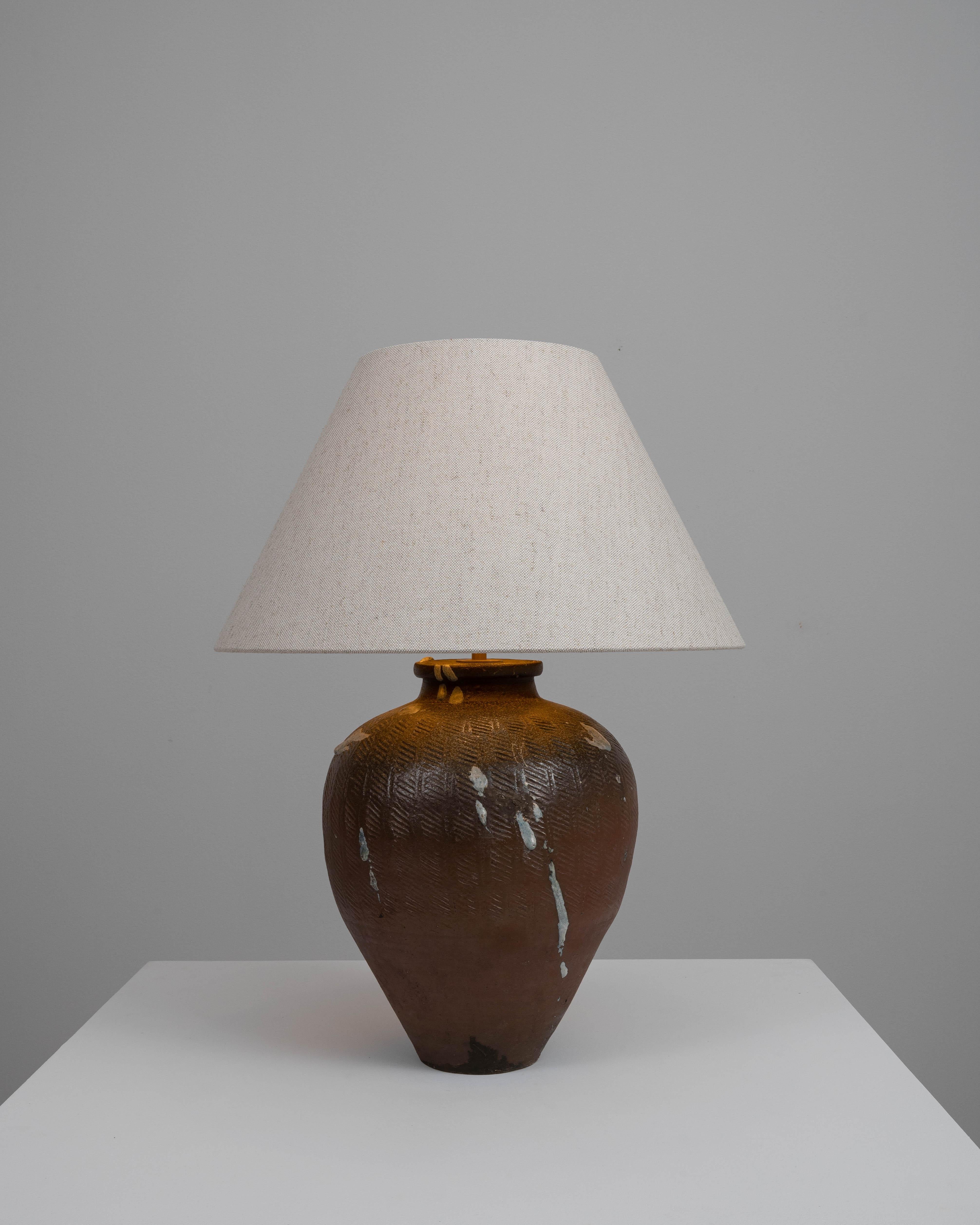 Elevate your decor with this authentically vintage 20th Century German Ceramic Table Lamp, a striking testament to timeless design and craftsmanship. This lamp exudes a rustic charm, featuring a stout, ovoid ceramic body adorned with a unique,