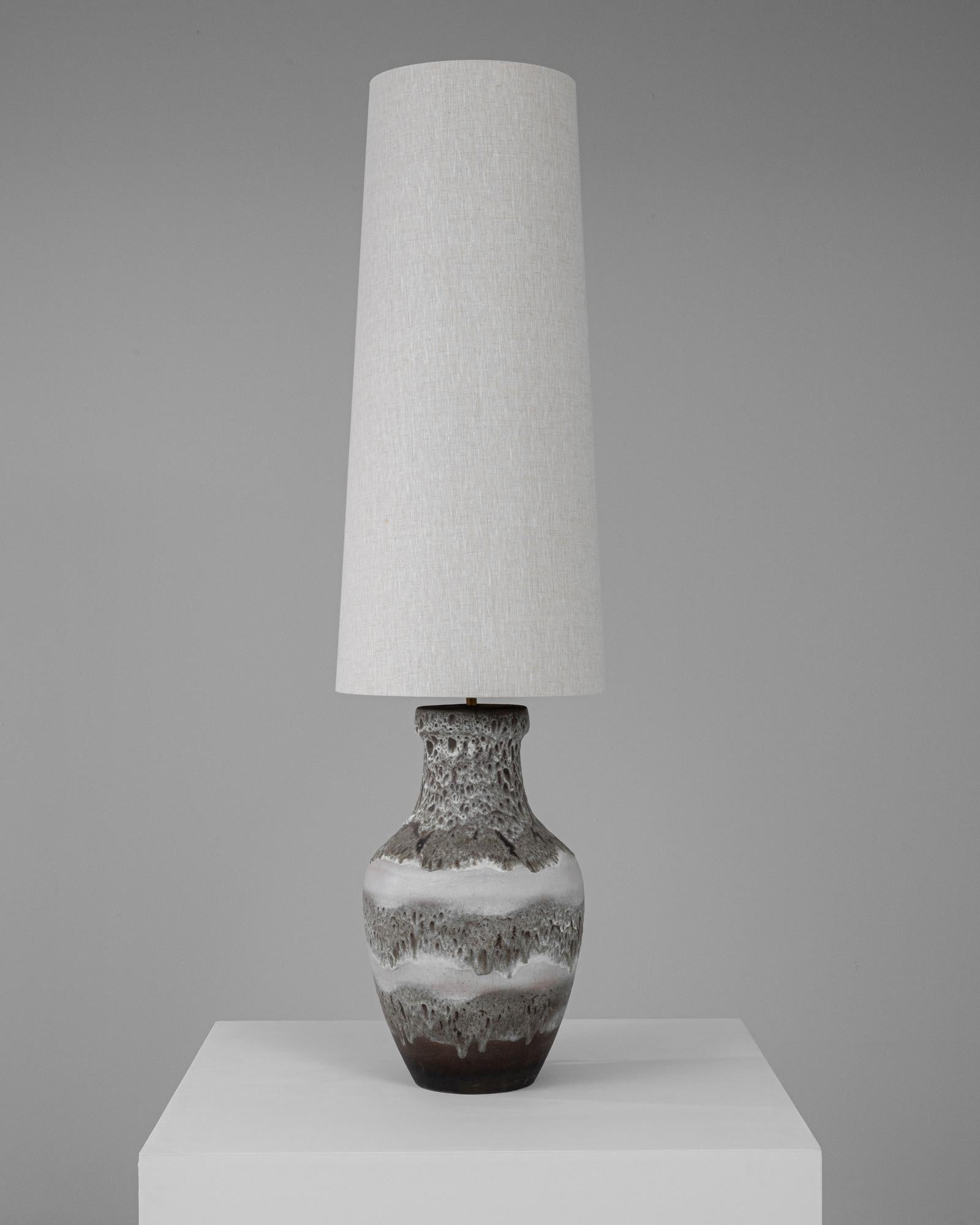 Cette lampe de table en céramique allemande du 20e siècle est un exemple exceptionnel de sophistication vintage mêlée à une fonctionnalité moderne. La base de la lampe est magnifiquement fabriquée en céramique avec une finition texturée qui présente