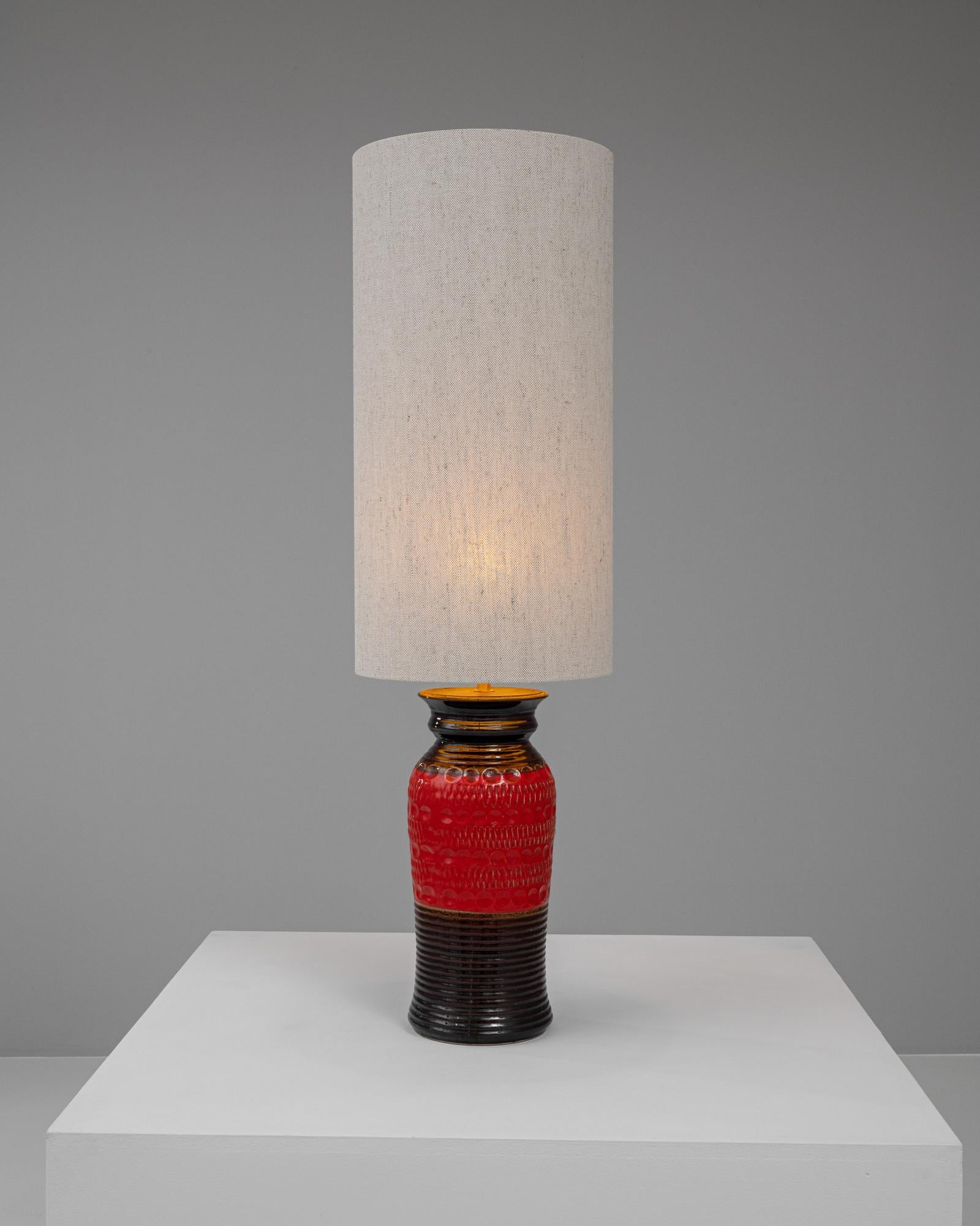 Añade un toque de color y sofisticación a tu decoración con esta impresionante lámpara de sobremesa de cerámica alemana del siglo XX. Con una vibrante base de cerámica roja con un patrón texturizado único, esta lámpara logra un equilibrio entre la