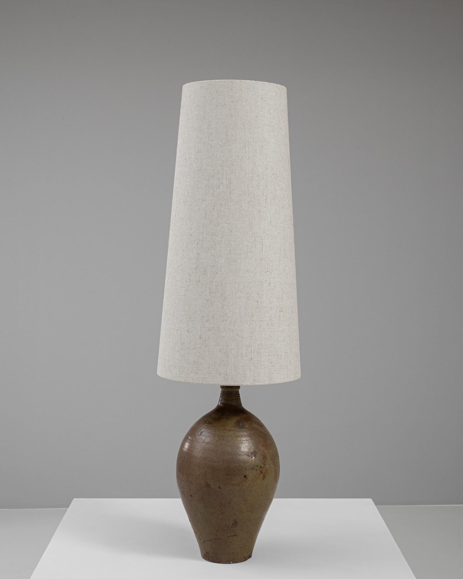 Cette lampe de table en céramique allemande du 20e siècle dégage un charme rustique qui s'intègre magnifiquement à toute décoration intérieure. La base de la lampe est fabriquée en céramique avec une finition naturelle et terreuse qui présente des