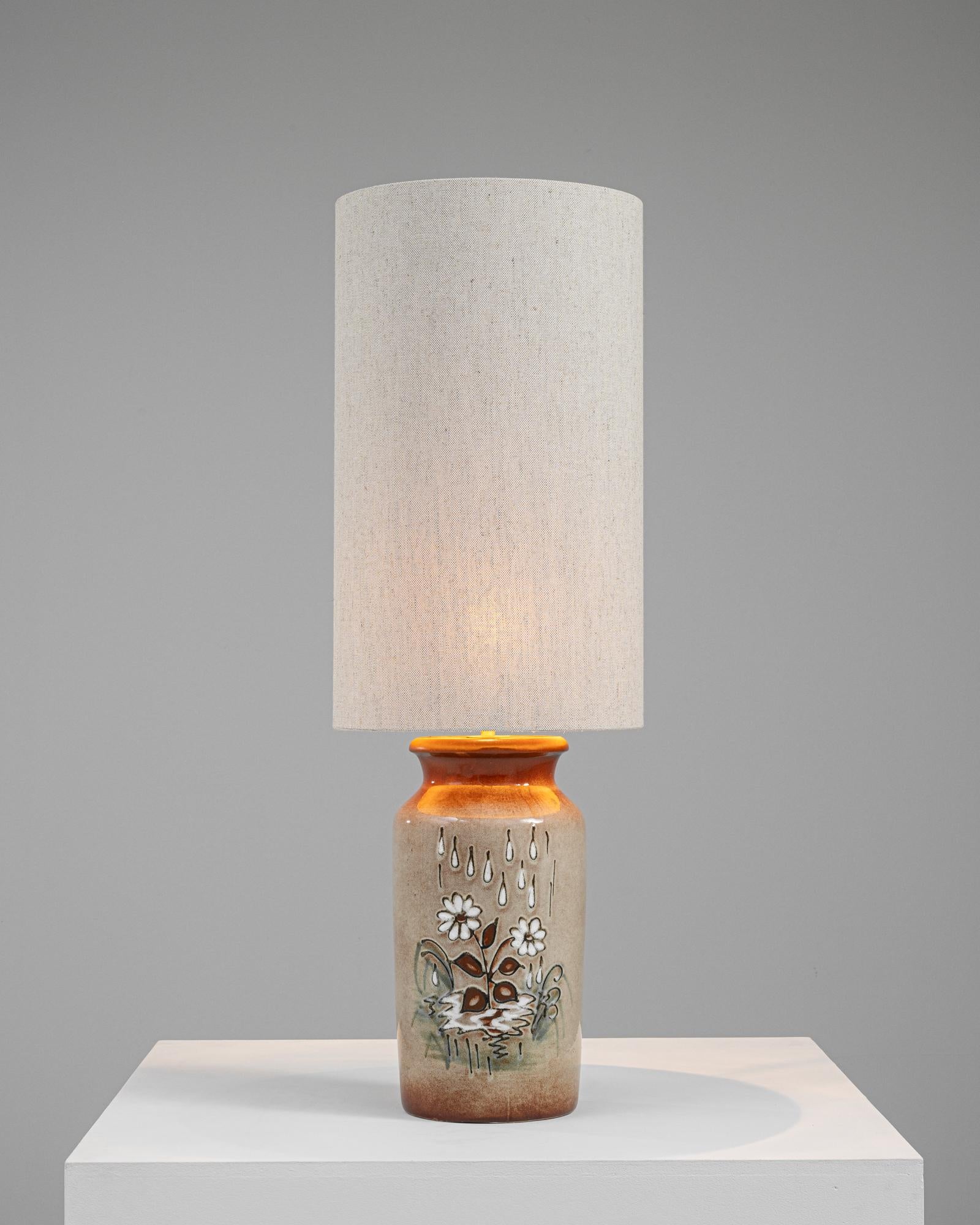 Cette lampe de table en céramique allemande du XXe siècle, magnifiquement fabriquée, apporte une fusion d'art et d'éclairage à tout espace. La lampe est dotée d'une base robuste en céramique, peinte avec soin d'un motif rustique d'inspiration