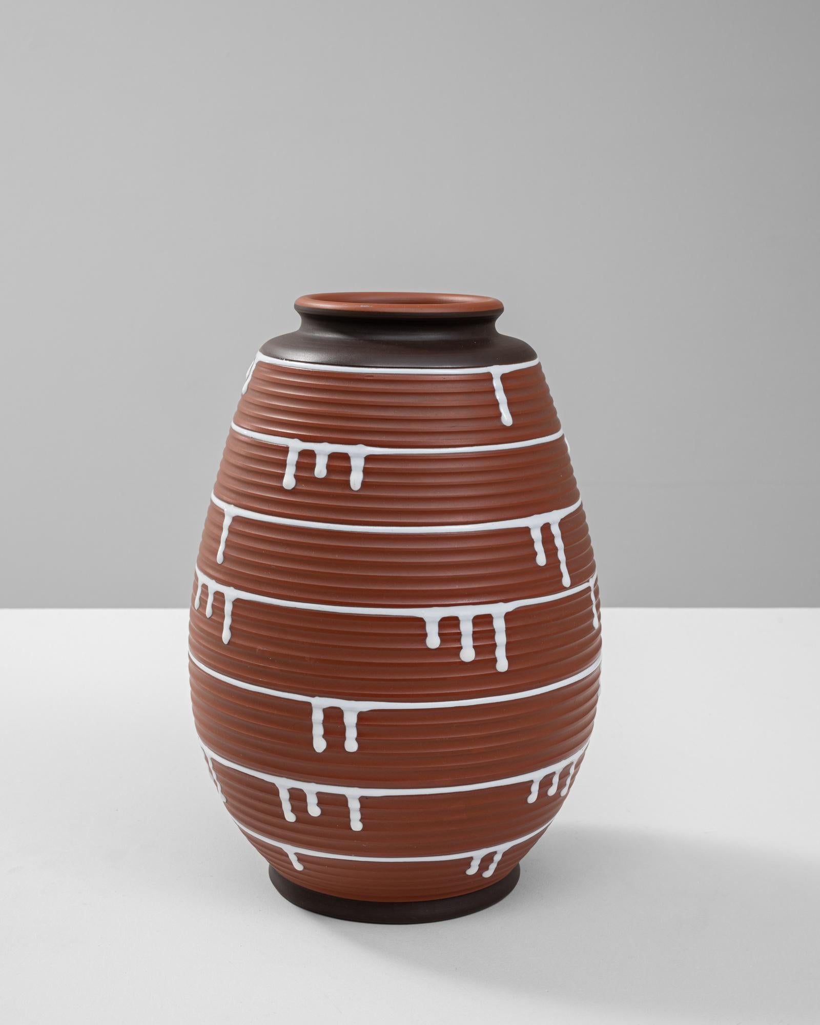 Questo vaso in ceramica tedesca del XX secolo è un esempio lampante di design moderno di metà secolo, che combina texture audaci con un'estetica giocosa. Il corpo color terracotta è caratterizzato da creste orizzontali che creano una superficie