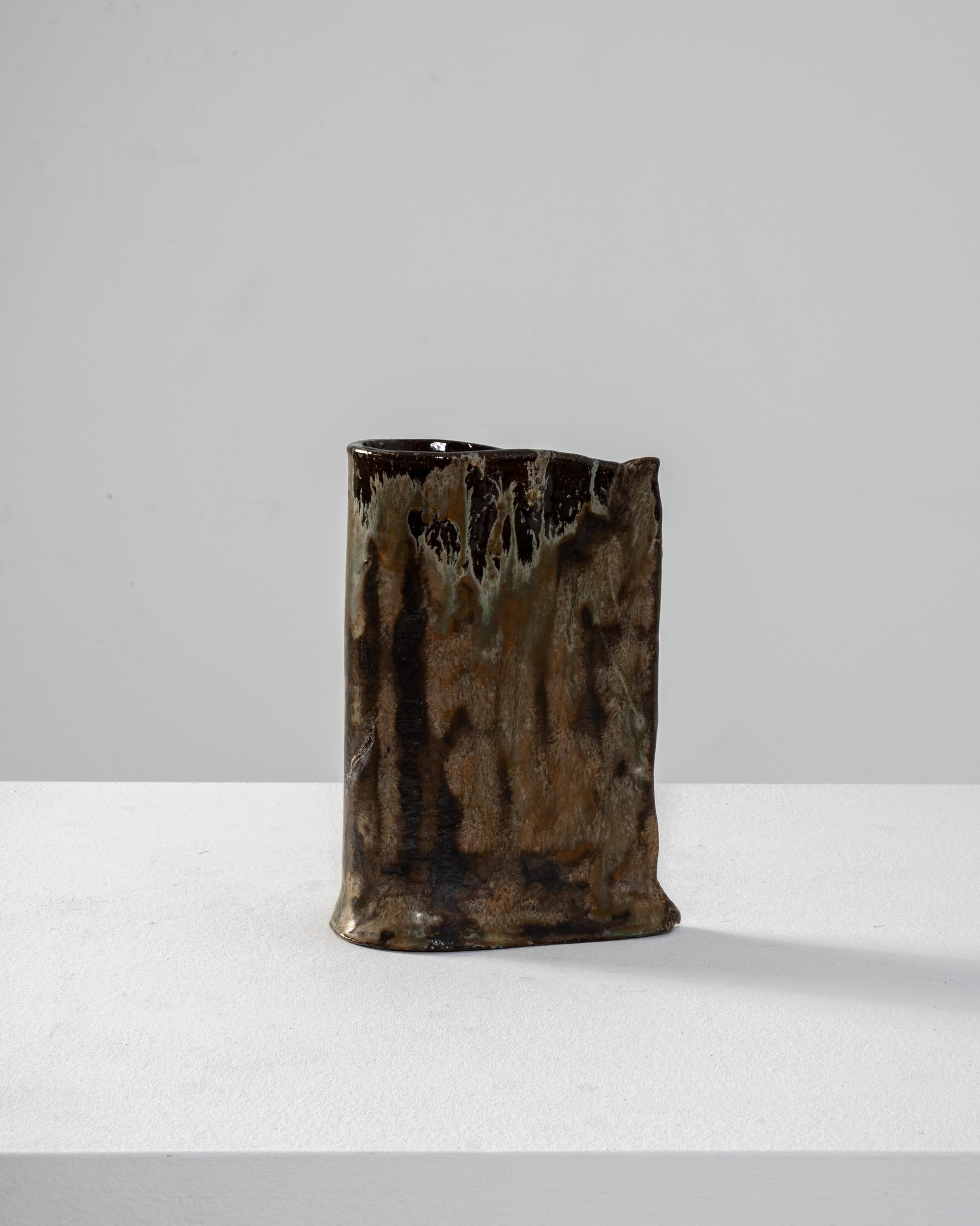 Dark clay and an unusual, textural glaze lend this Organic Modern ceramic vase an attractive intensity. Made in Germany in the 20th century, the form itself is crude and asymmetric, deliberately naive. A single sheet of clay is doubled back on