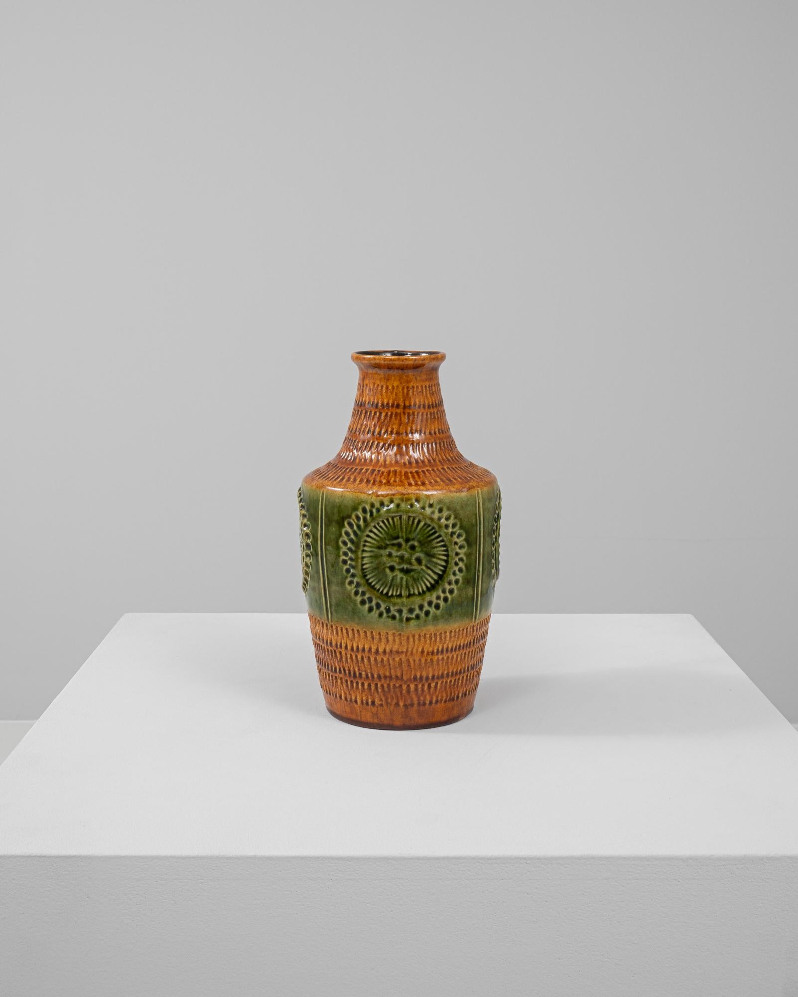 Esta jarra de cerámica alemana del siglo XX muestra el vibrante arte de la cerámica de Alemania Occidental. Su intrincado diseño presenta una banda texturizada de cálidos tonos terracota, complementada por un cuerpo verde ricamente esmaltado