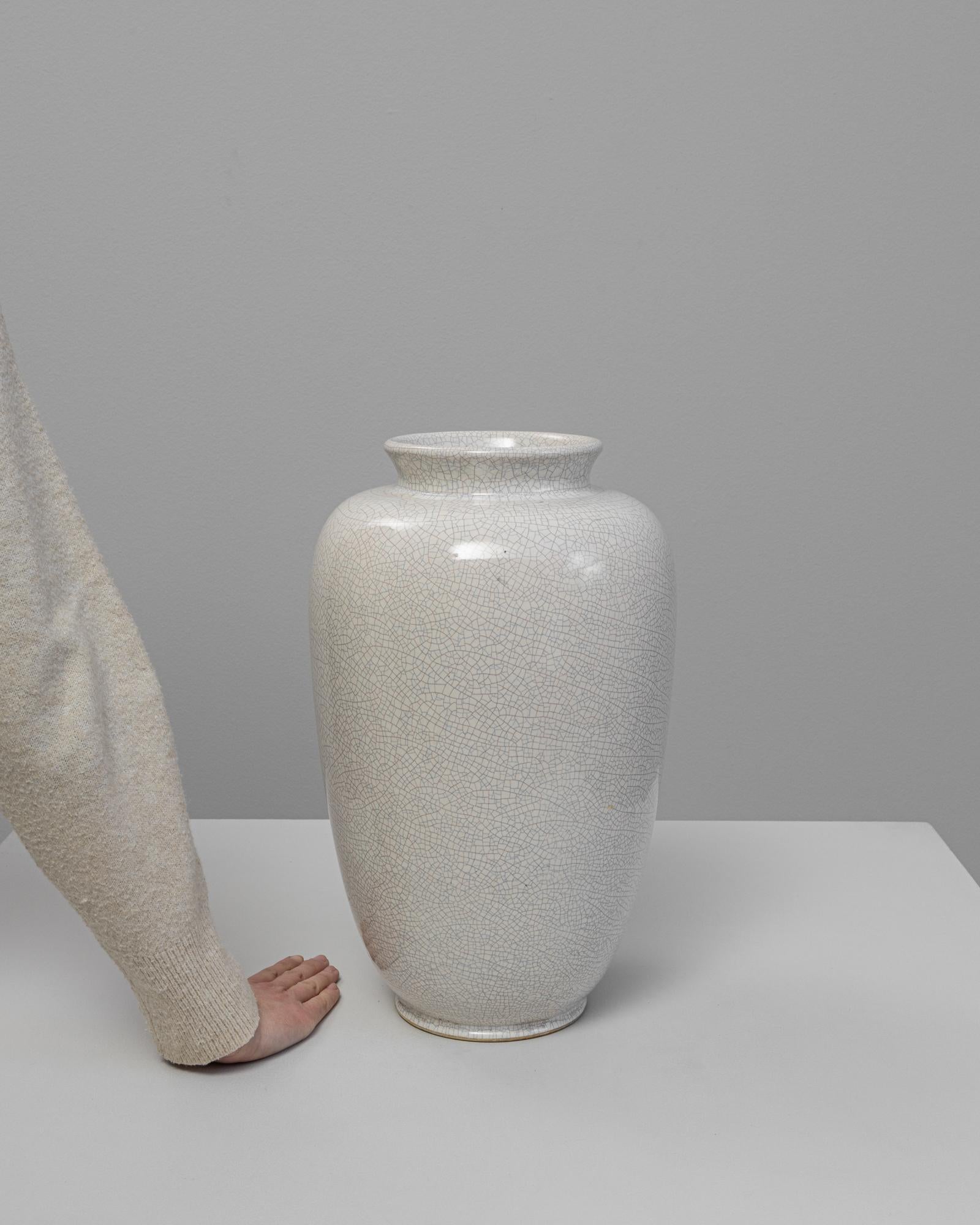 Vaso in ceramica tedesca del XX secolo. Questo elegante vaso presenta una raffinata silhouette a balaustro con un bordo dolcemente svasato e un delicato smalto crepla nei toni dell'avorio e del blu chiaro. L'intricata rete di sottili screpolature