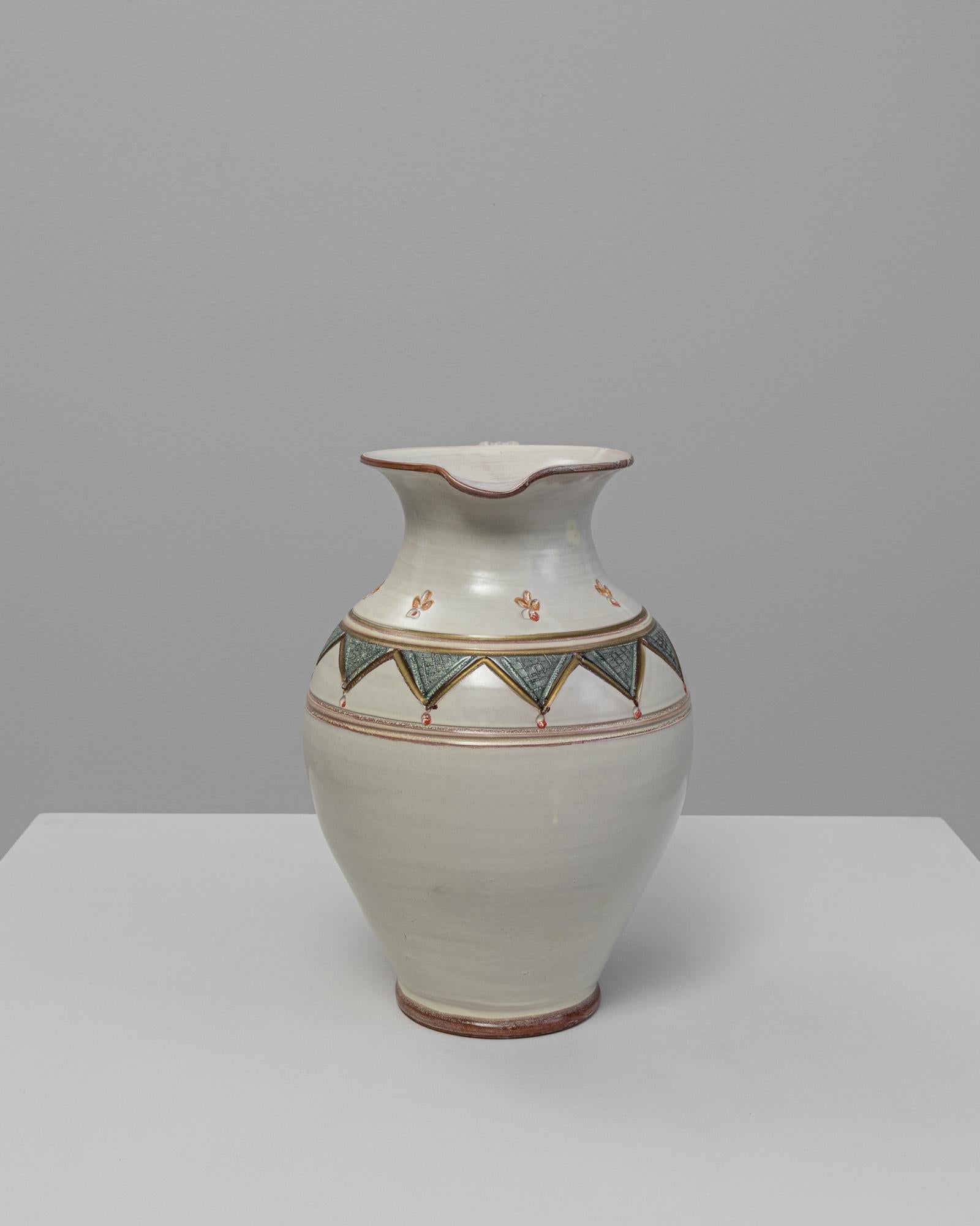 Vaso in ceramica tedesca del XX secolo. Questa elegante brocca in ceramica presenta un morbido smalto color crema accentuato da motivi geometrici e floreali dipinti a mano nei toni del verde, della terracotta e dell'oro. Il design combina una