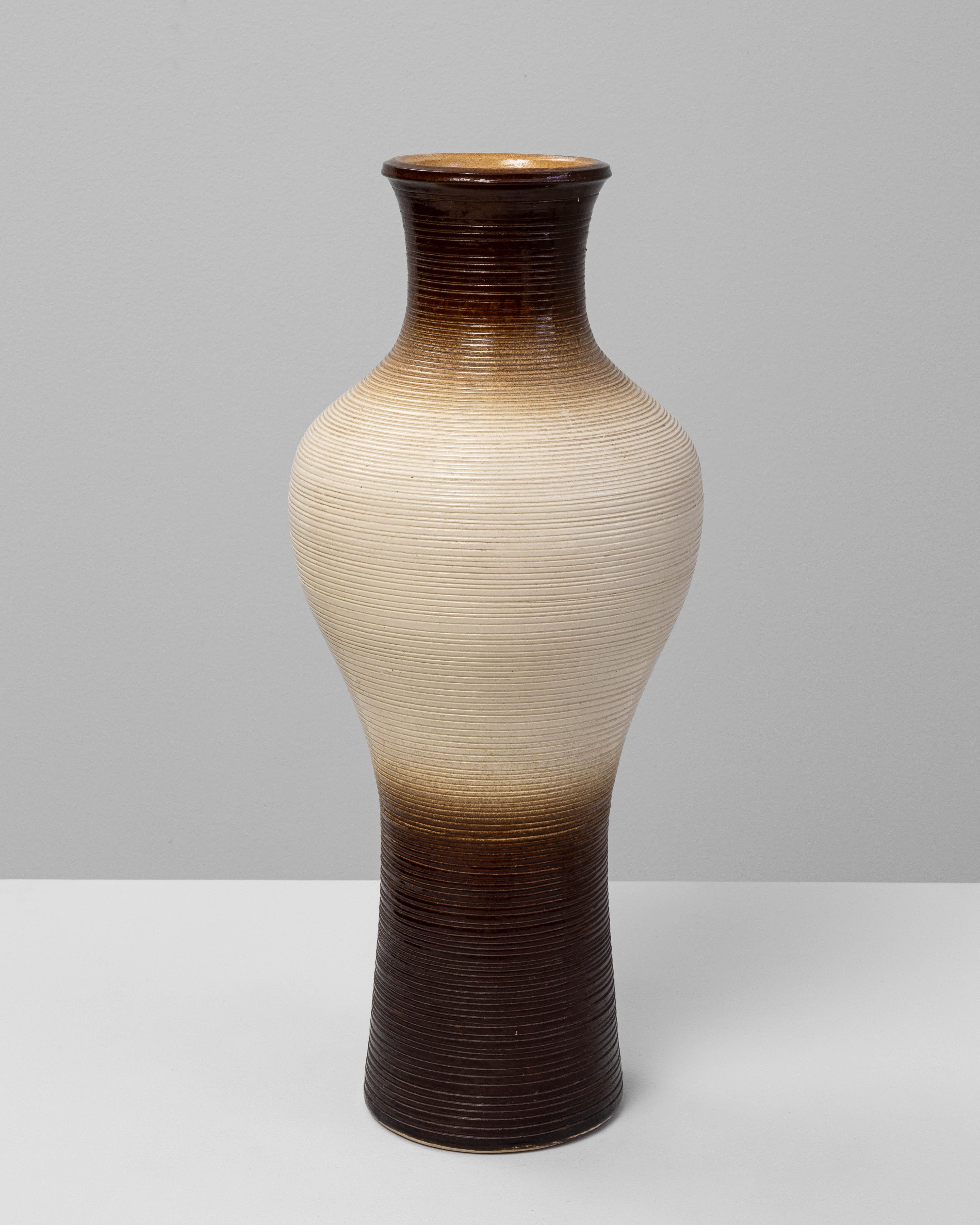 Jarrón de cerámica alemana del siglo XX que muestra la refinada artesanía y la estética terrosa características de la cerámica europea de mediados de siglo. El jarrón presenta una superficie estriada con un suave esmalte degradado que pasa del rico