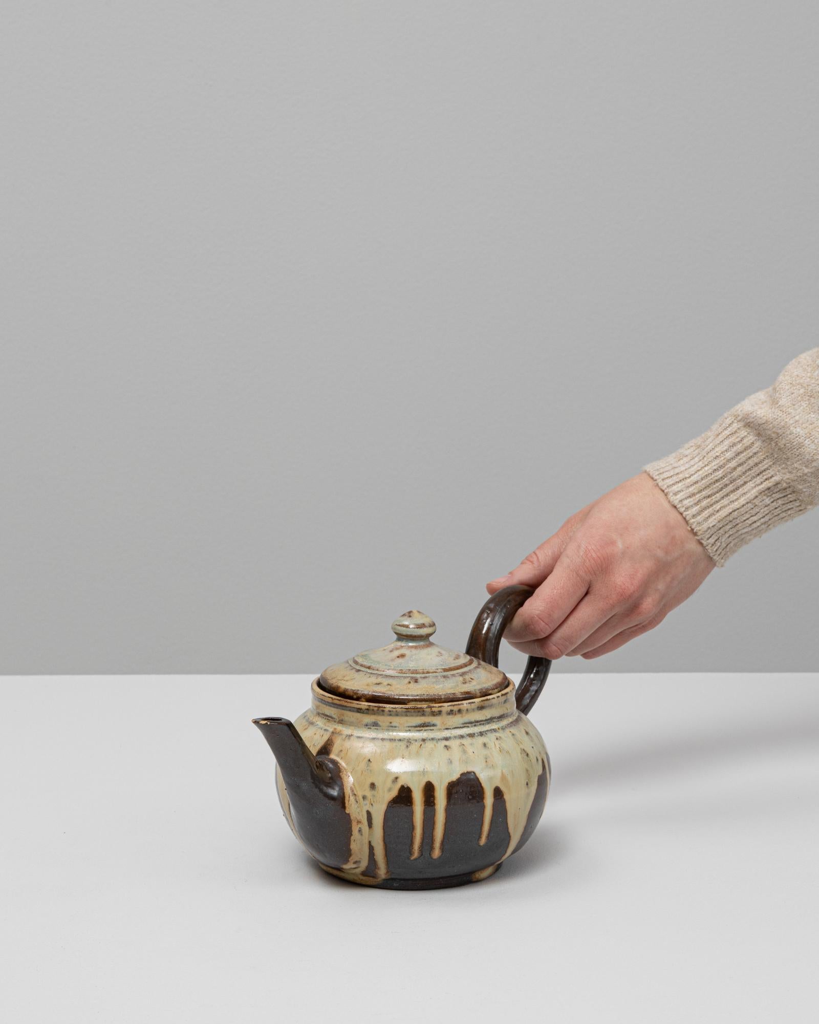 Cette cruche en céramique à glaçure goutte à goutte allemande du 20e siècle avec couvercle illustre les techniques de glaçure expressives qui ont défini une grande partie de la poterie d'atelier européenne du milieu du siècle. Son corps arrondi et