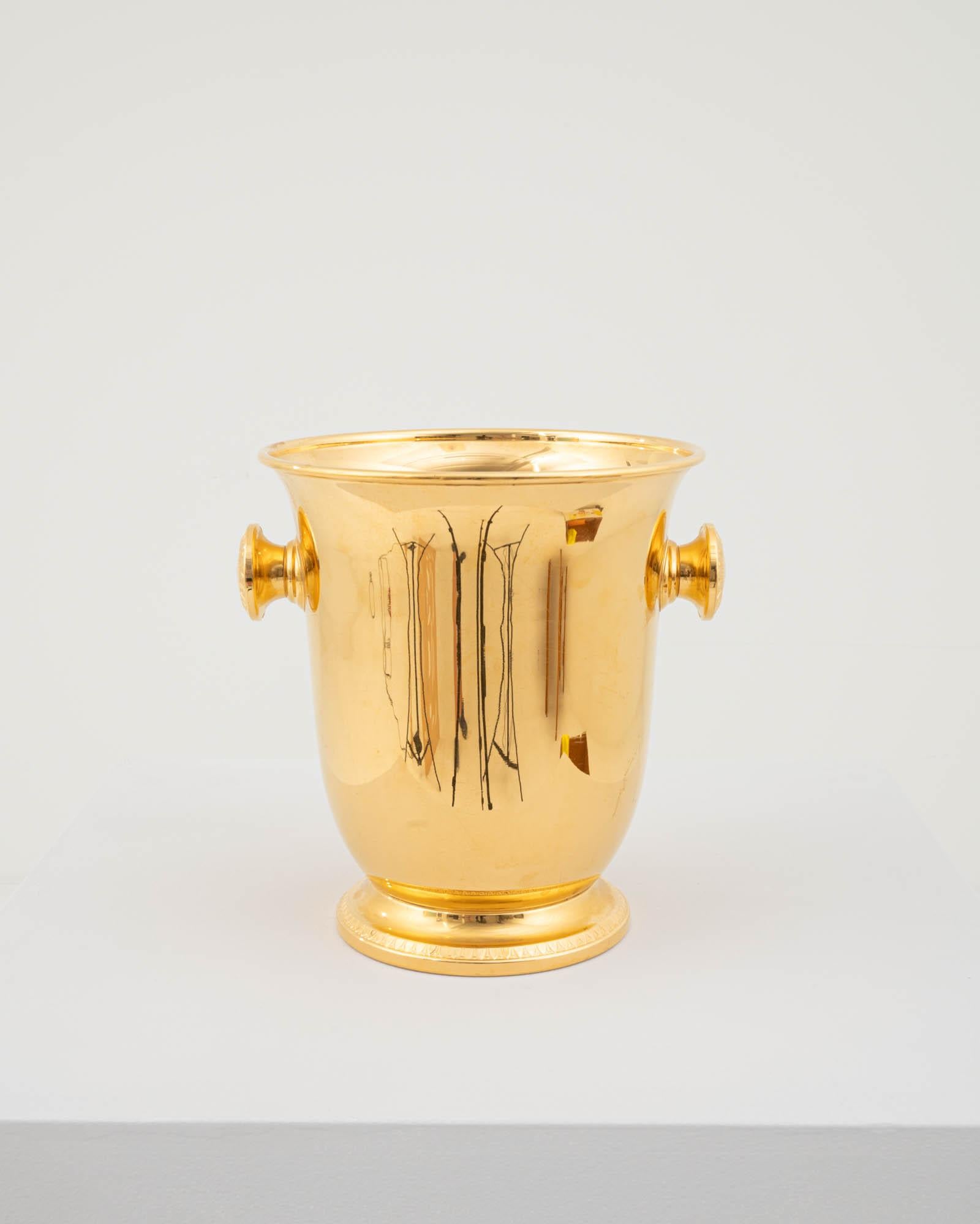 This exquisite vintage ice bucket was designed in Germany during the 20th century. Crafted from high-quality metal, the bucket is coated with a layer of gold plating for a luxurious finish. The edges of the base and elegantly rounded handles are