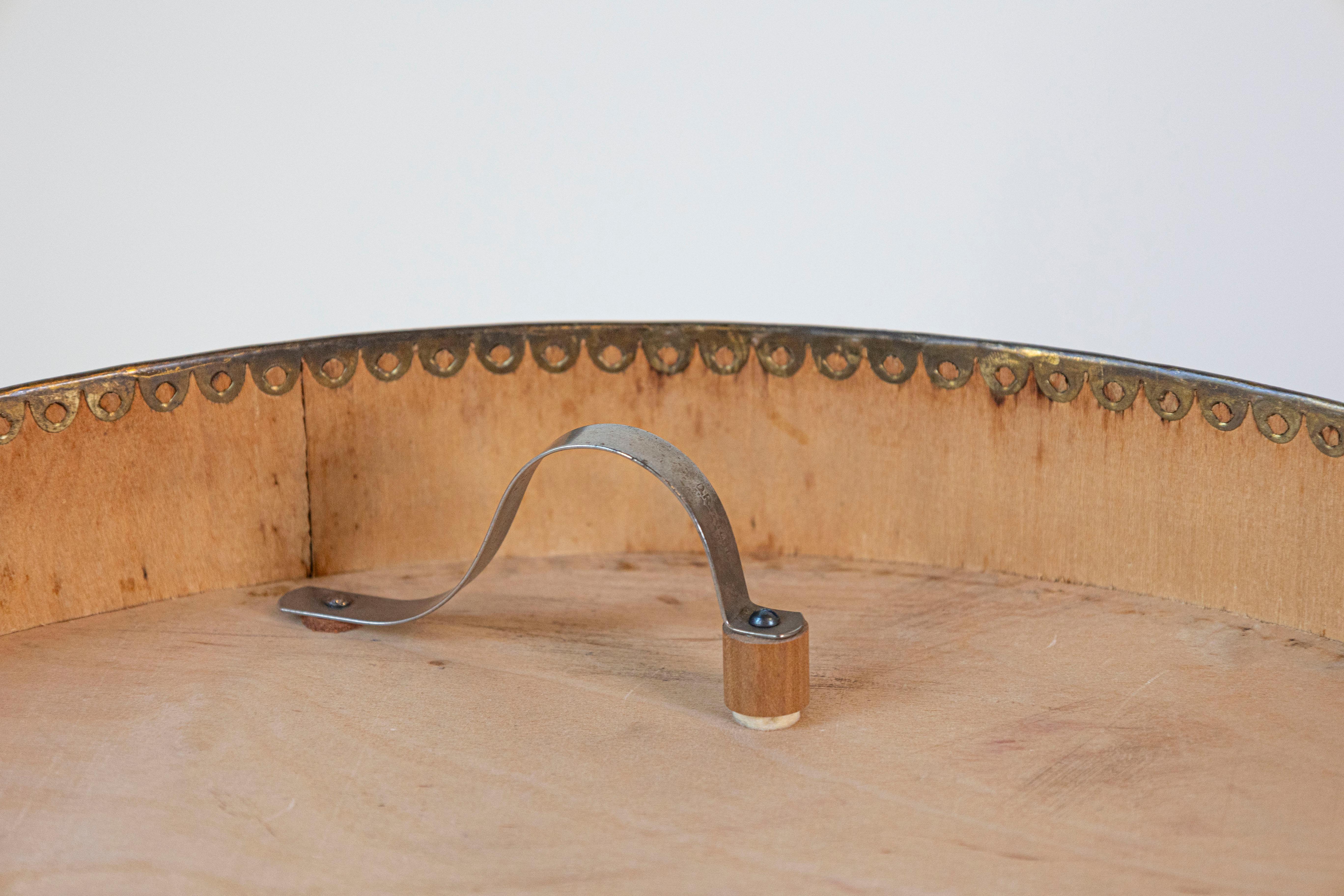 This charming 20th-century German hat box is a wonderful example of vintage travel and storage accessories. Crafted from sturdy and lightweight materials, the cylindrical box features a warm wood-tone finish, accented by delicate decorative metal