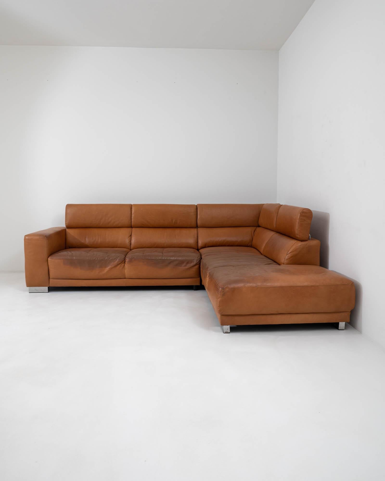Designed in 20th century Germany, this leather corner sofa showcases a captivating Tetris-like geometry punctuated by an L-shaped seating arrangement. The practical adjustment mechanism allows the height of the backrest to fold up and down for